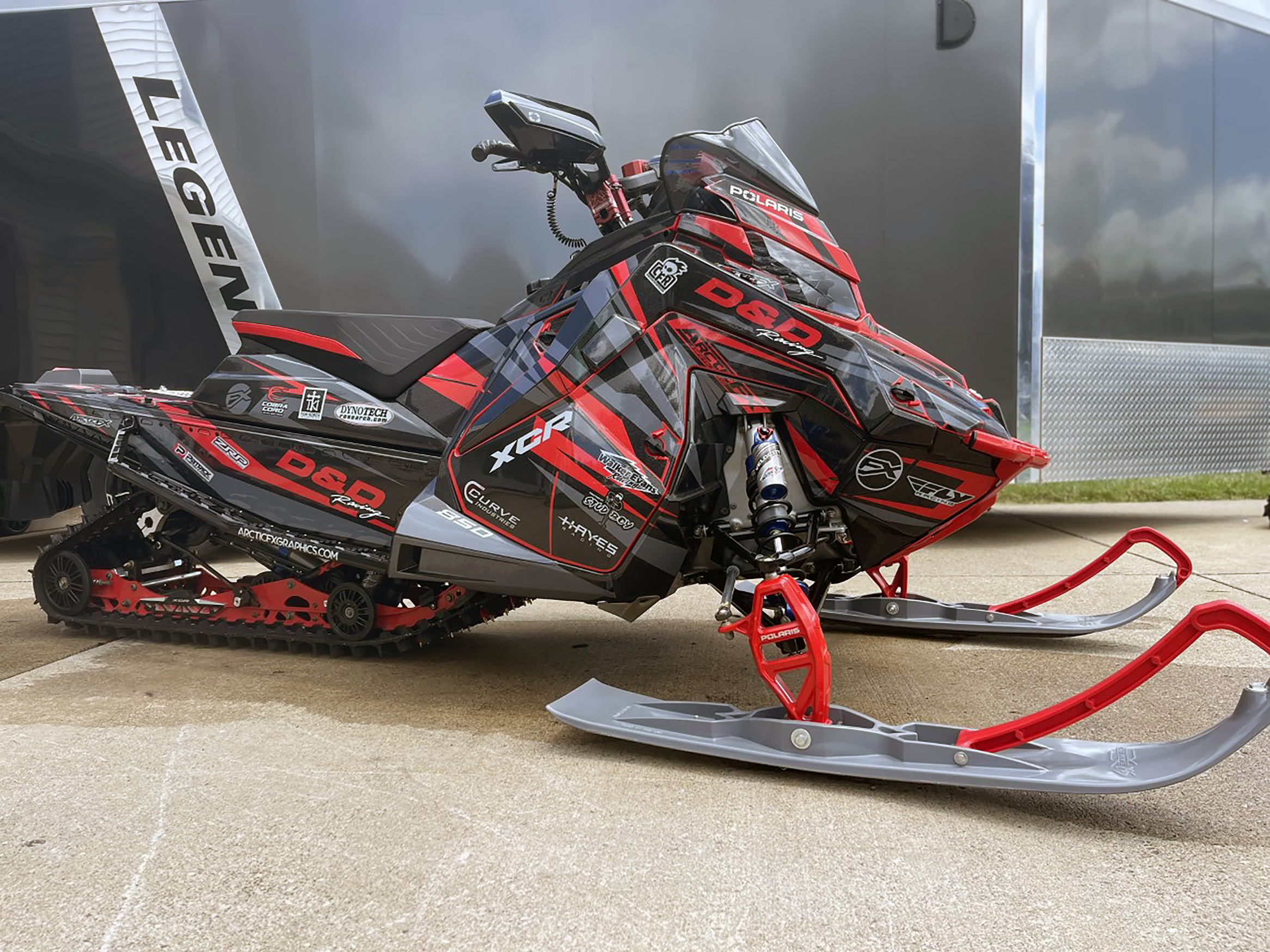 A Polaris Matryx Trail snowmobile with a red and black Burandt Evolution custom vinyl wrap.