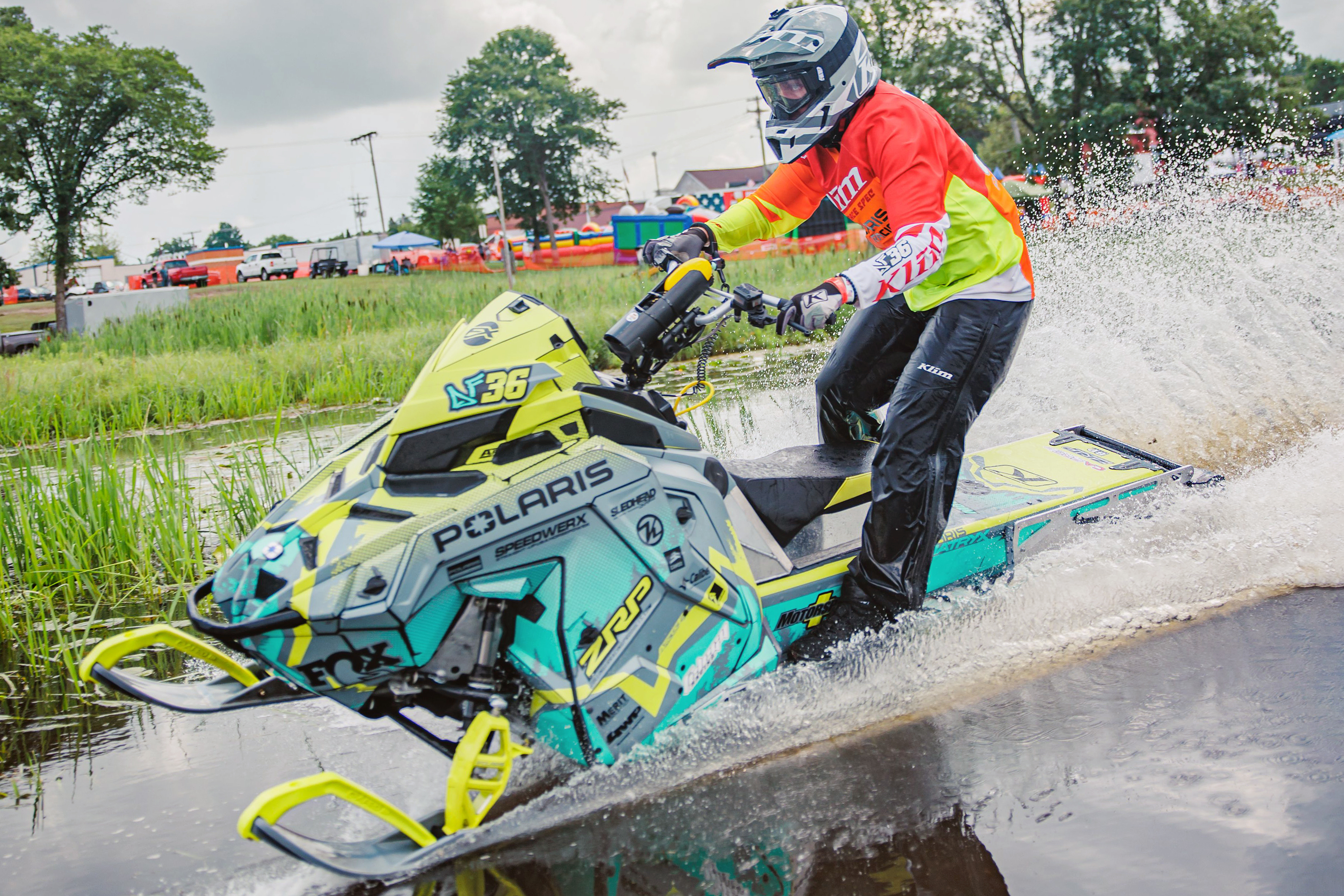 A Polaris Matryx Trail snowmobile with a aqua, lime squeeze, and black DF36 Psych custom vinyl wrap.
