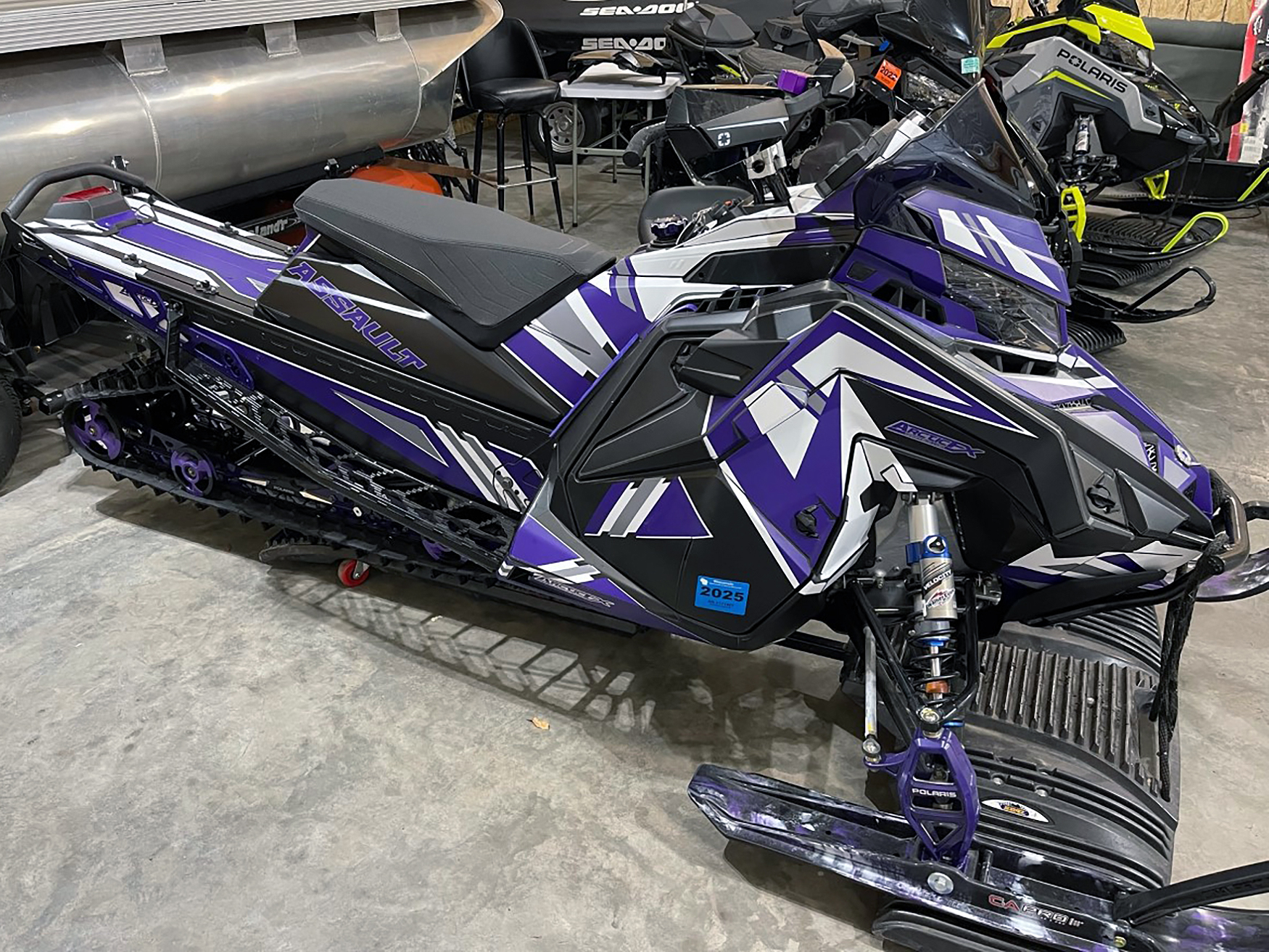 A Polaris Axys Trail snowmobile with a purple, white, and black Quantum custom vinyl wrap.
