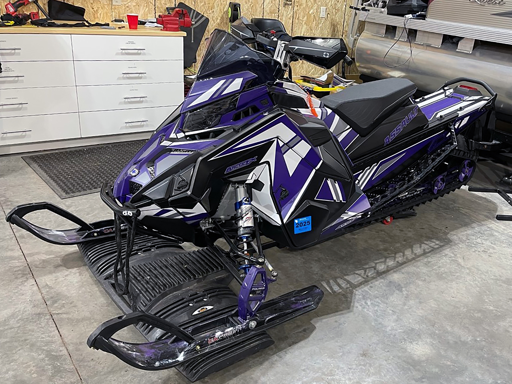 A Polaris Axys Trail snowmobile with a purple, white, and black Quantum custom vinyl wrap.