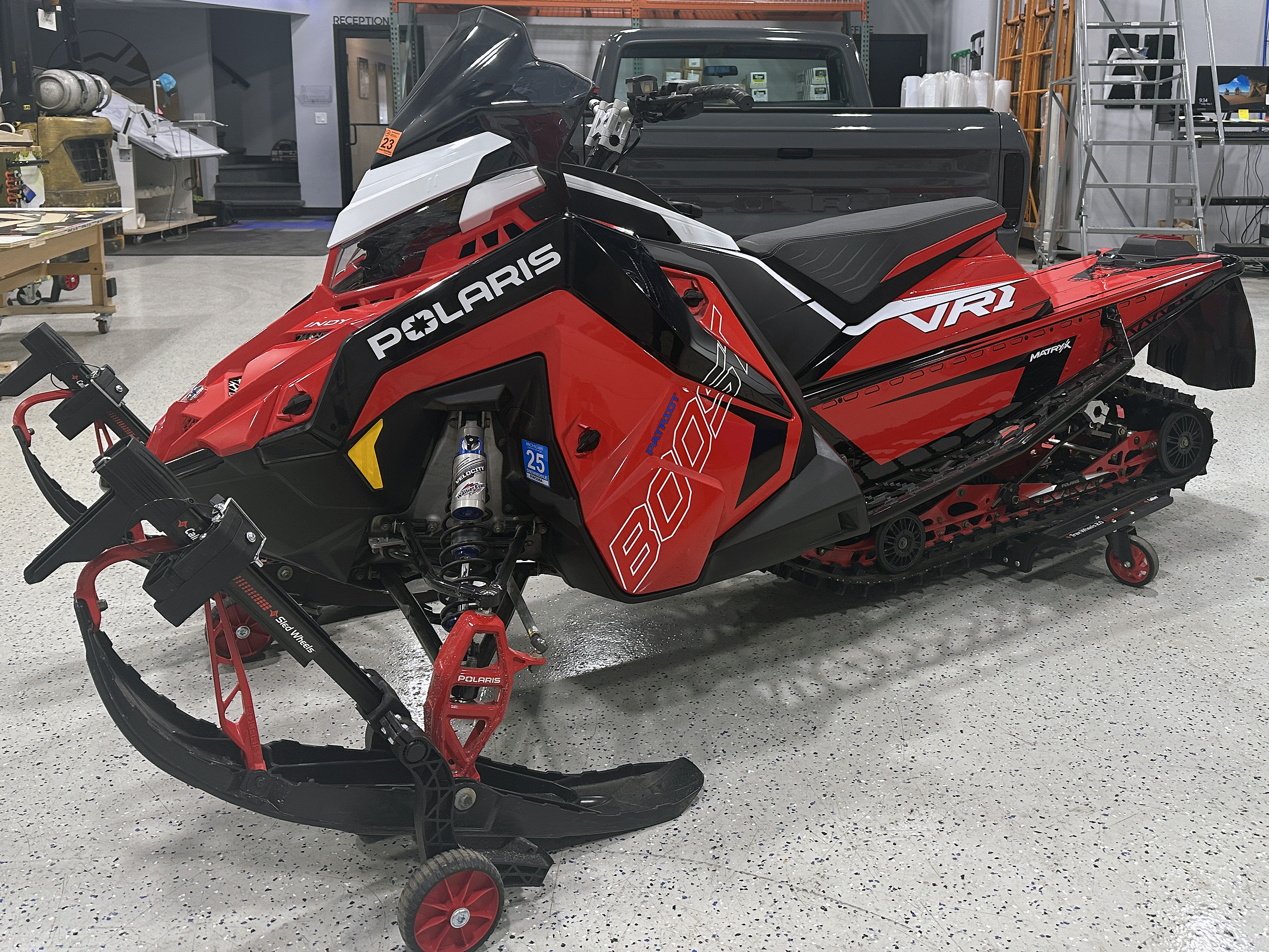 A Polaris Axys Trail snowmobile with a red, white, and black Stock Match custom vinyl wrap.