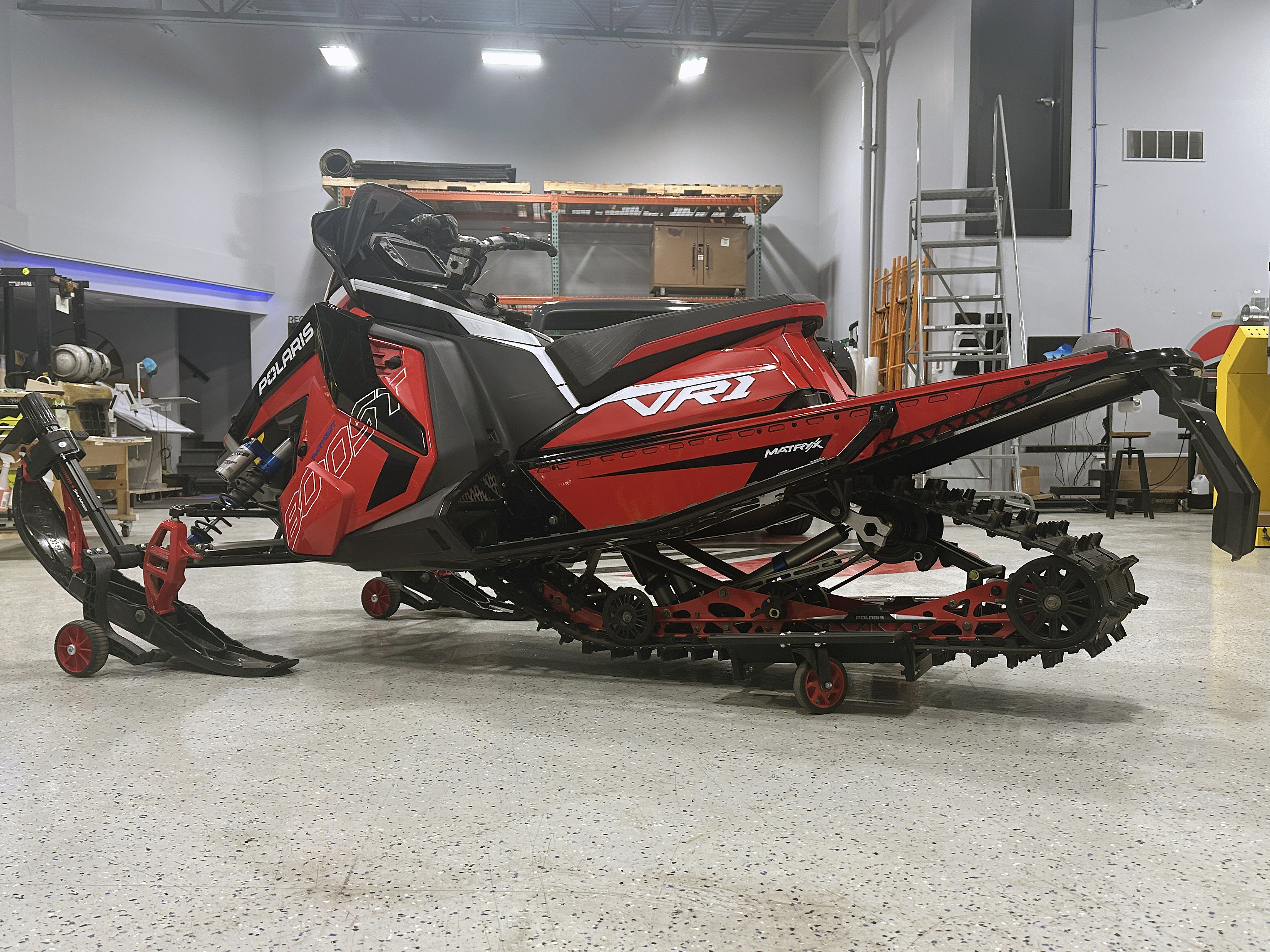 A Polaris Axys Trail snowmobile with a red, white, and black Stock Match custom vinyl wrap.