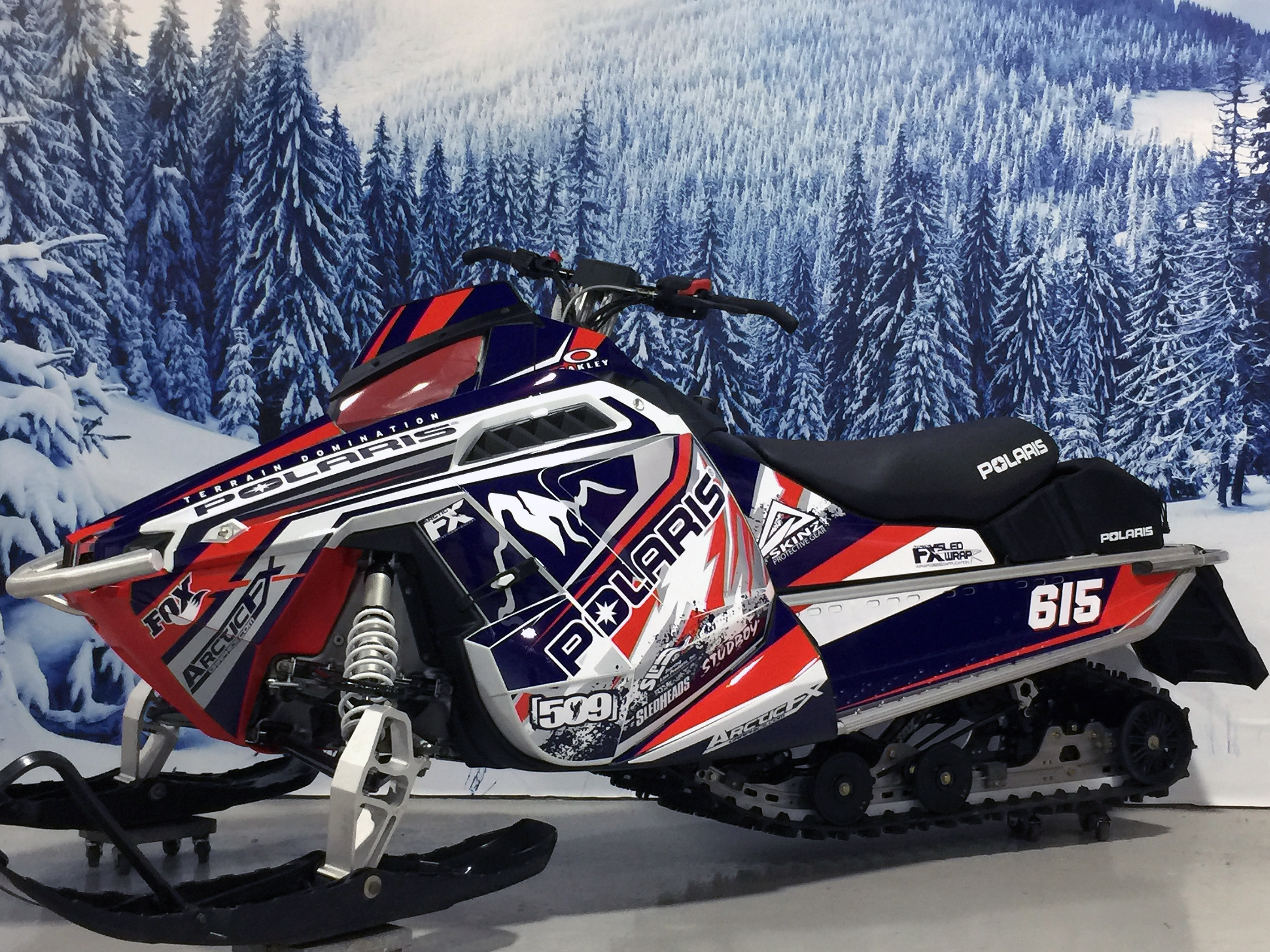 A Polaris Pro-Ride snowmobile with a retro blue, red, and white Adams Signature custom vinyl wrap.