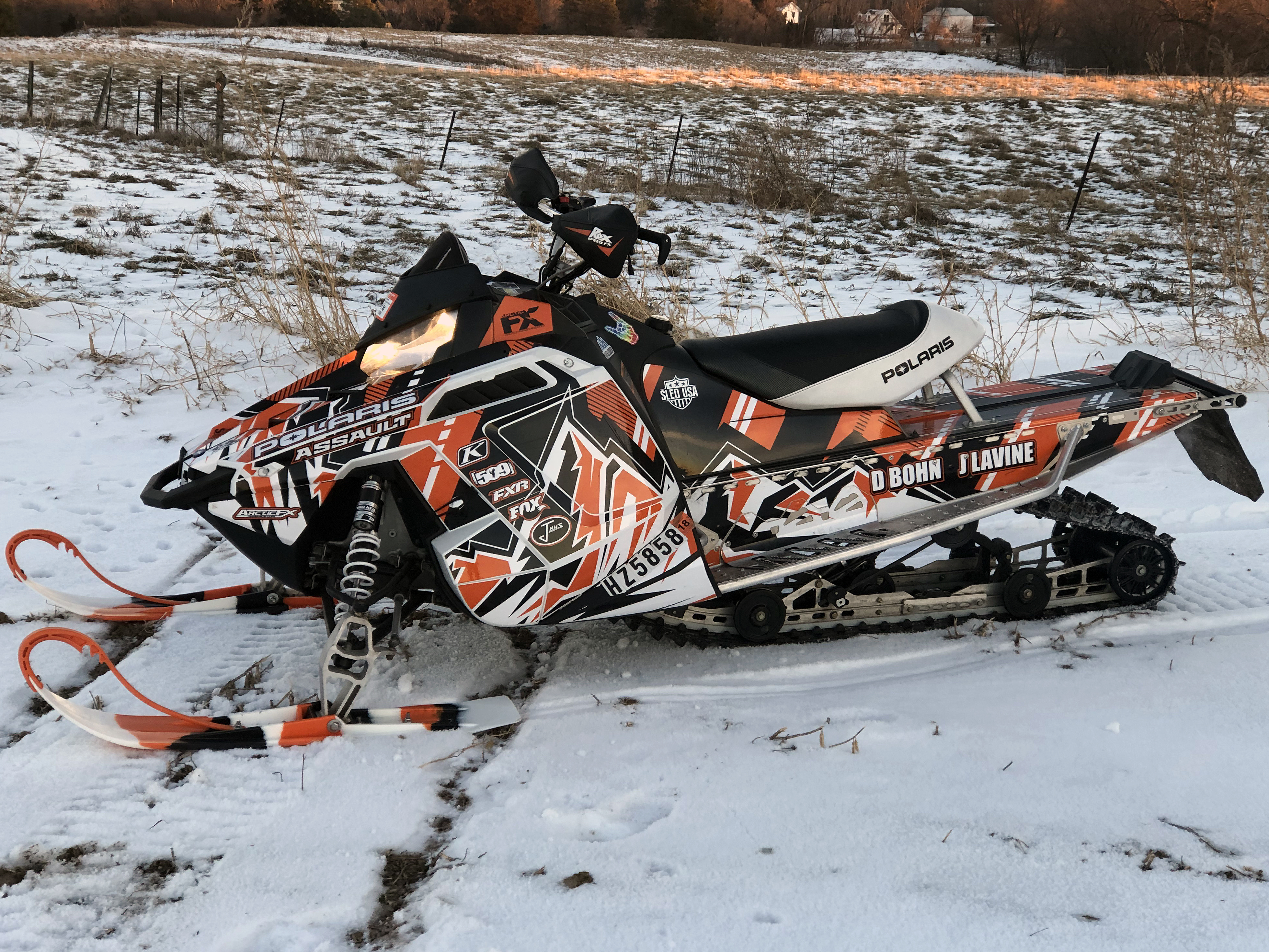 A Polaris Pro-Ride snowmobile with a orange, black, and white Altitude City custom vinyl wrap.