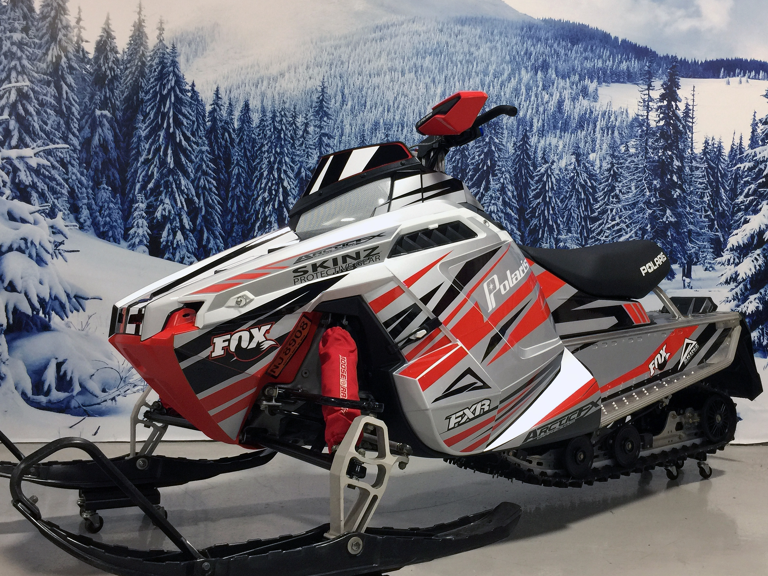 A Polaris Pro-Ride snowmobile with a red, black, and gray Burandt Evolution custom vinyl wrap.