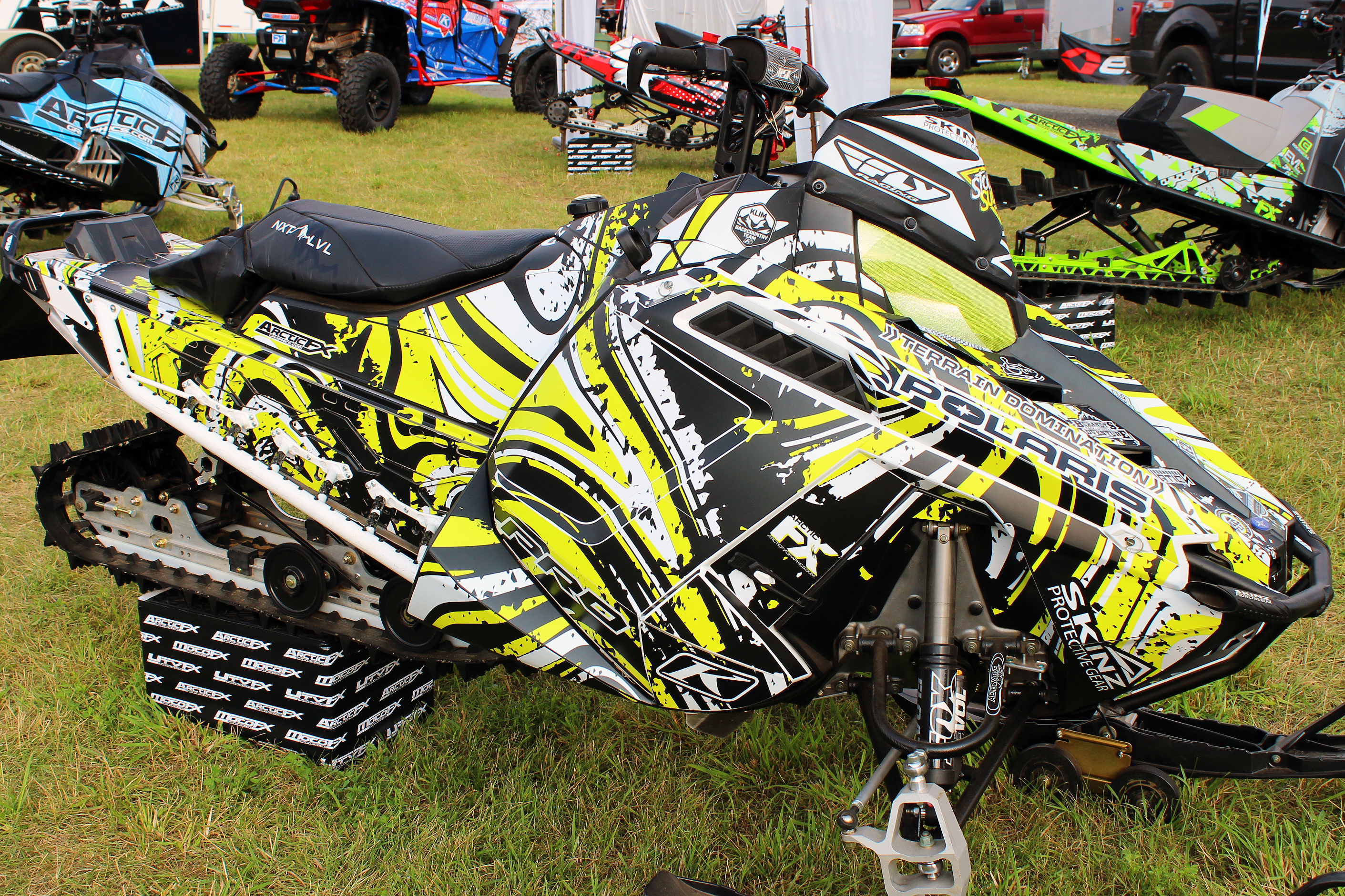 A Polaris Pro-Ride snowmobile with a lime squeeze, black, and white Flux custom vinyl wrap.