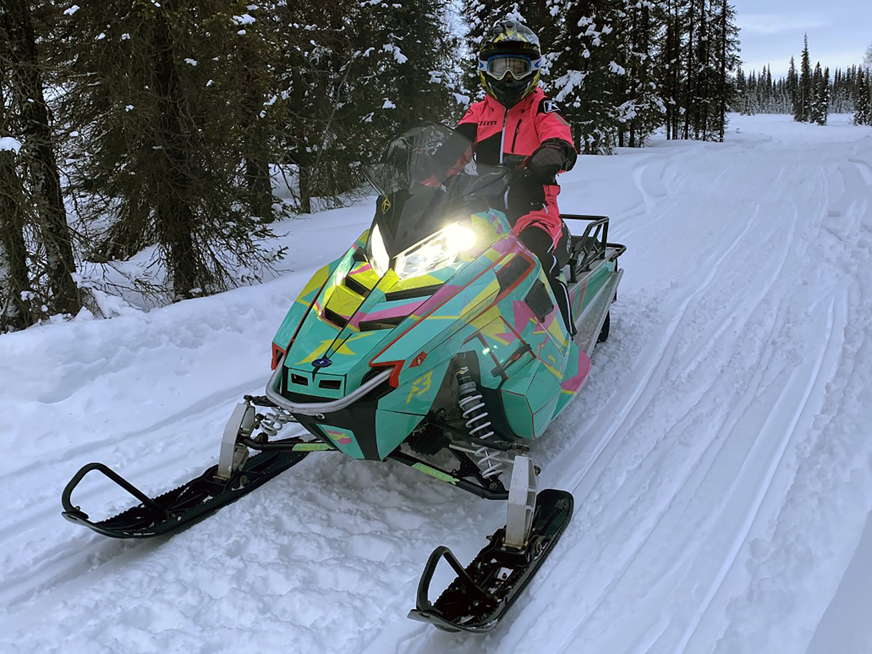 A Polaris Pro-Ride snowmobile with a aqua, pink, and lime squeeze Klim F3 Camo custom vinyl wrap.