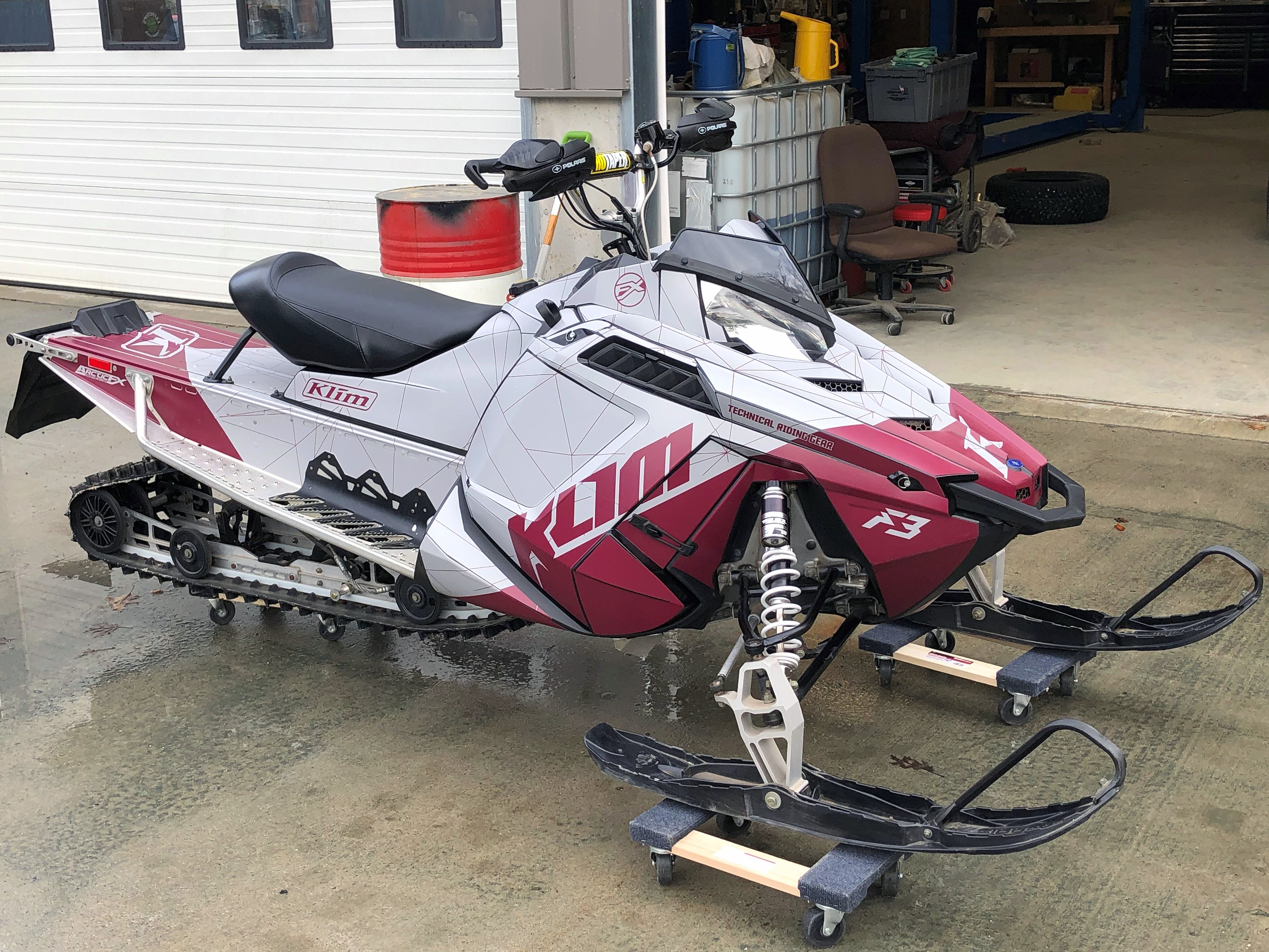 A Polaris Pro-Ride snowmobile with a white and burgundy Klim F3 Camo custom vinyl wrap.