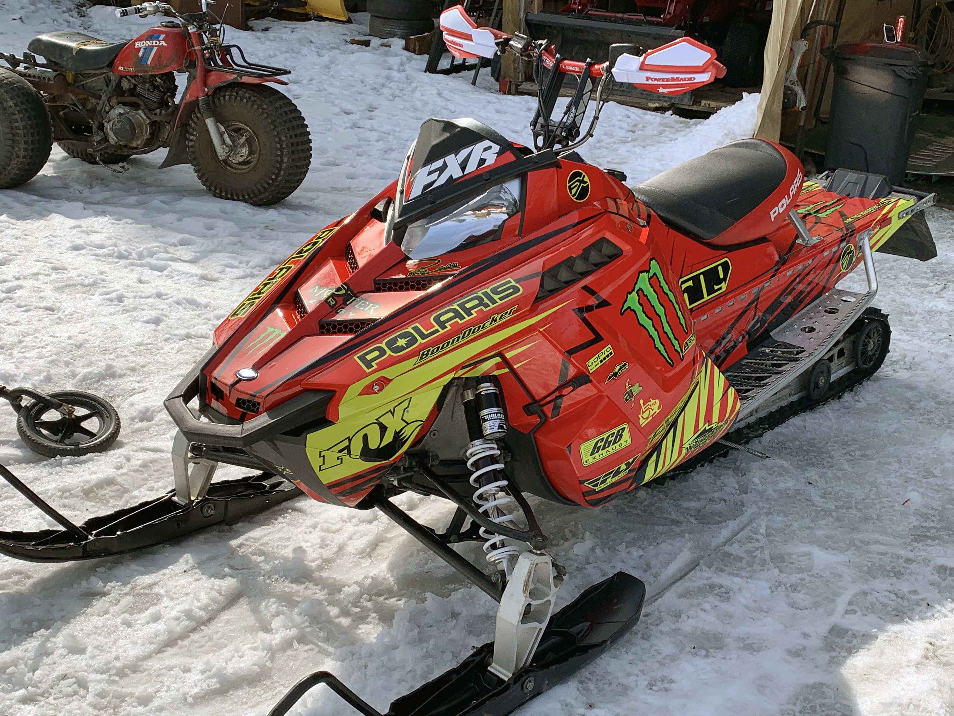 A Polaris Pro-Ride snowmobile with a lime squeeze, red, and black Kryptonite custom vinyl wrap.