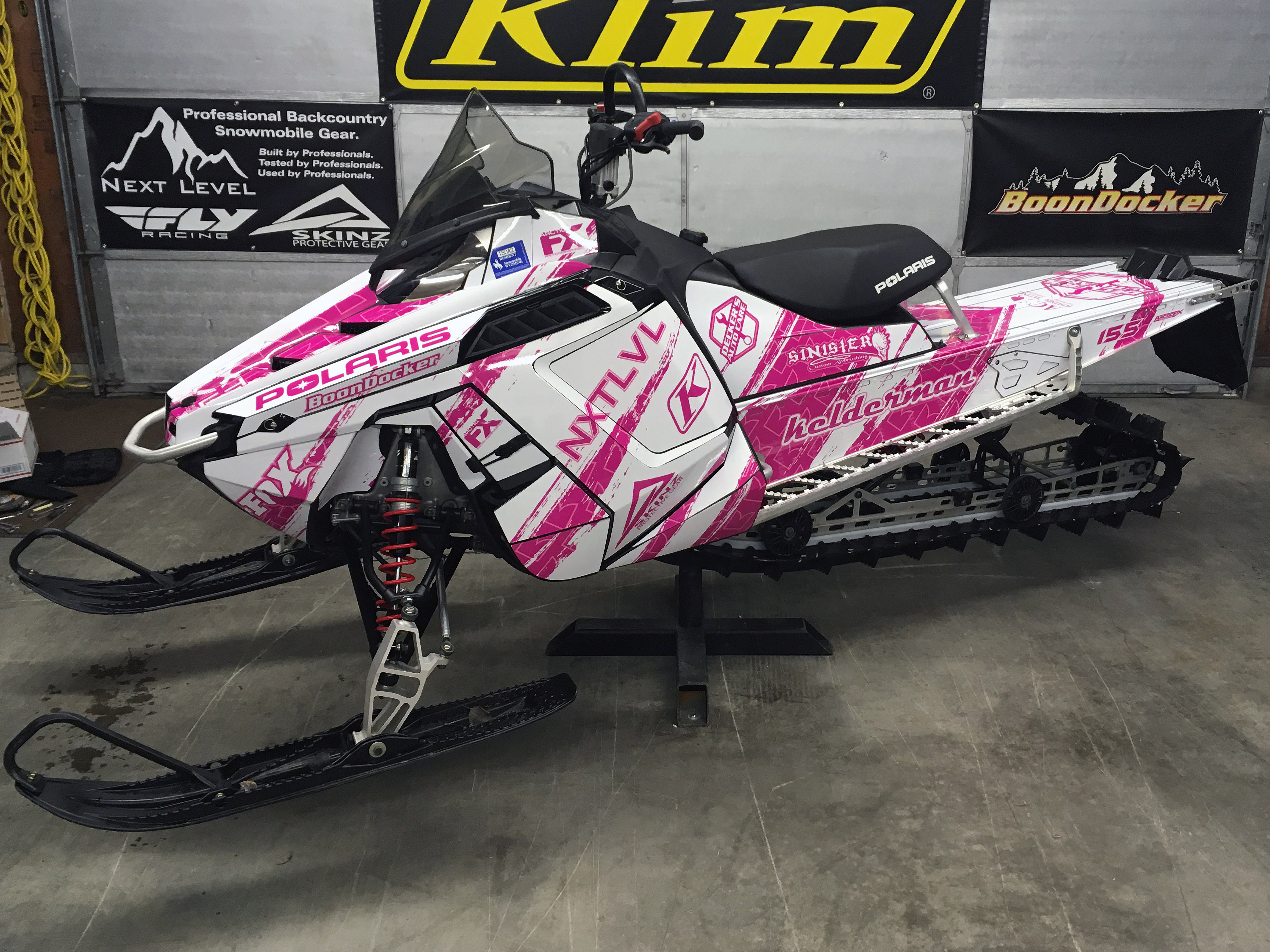 A Polaris Pro-Ride snowmobile with a pink and white Adams NXT LVL custom vinyl wrap.