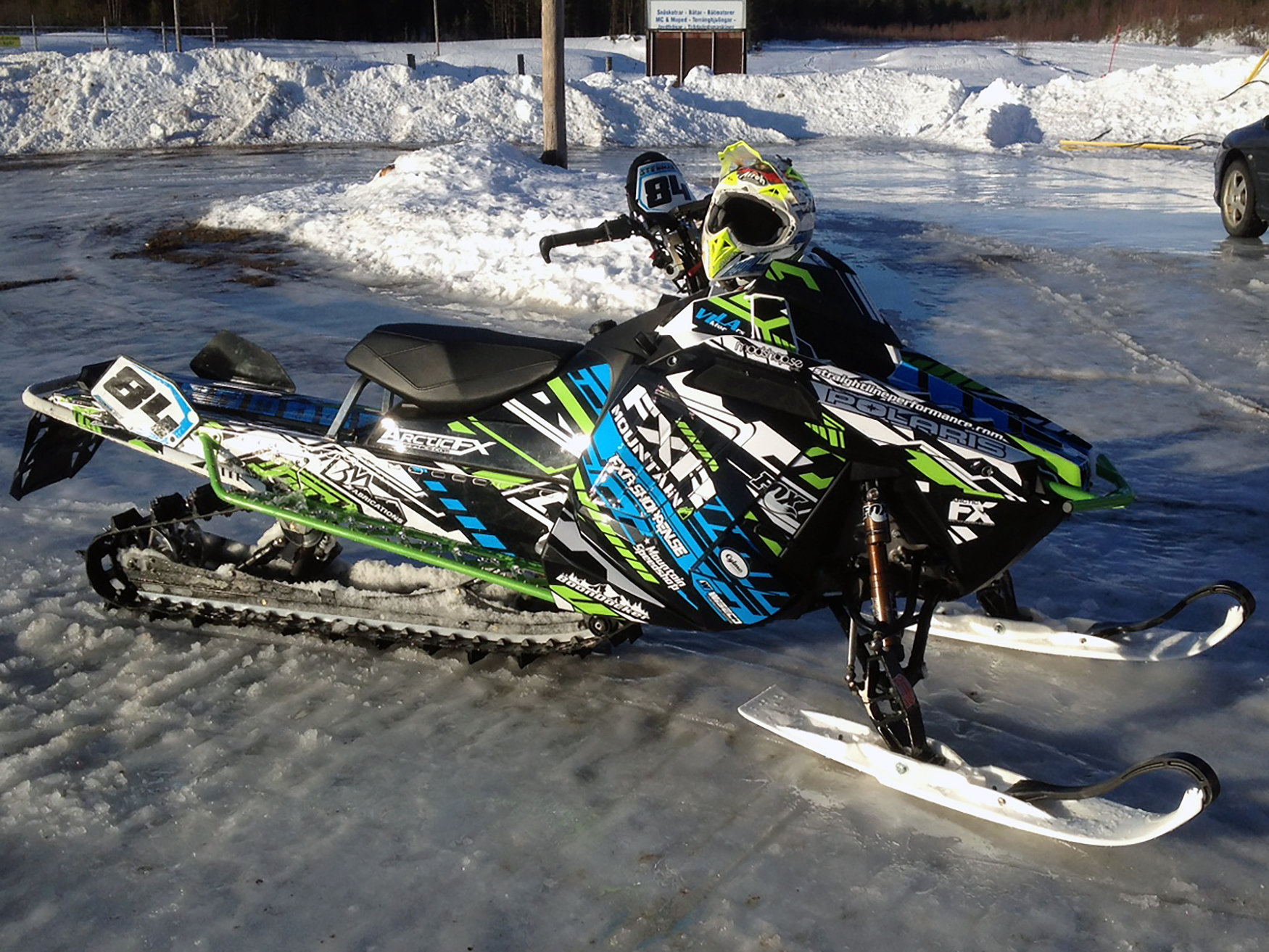 A Polaris Pro-Ride snowmobile with a blue, black, and lime squeeze Evasion custom vinyl wrap.