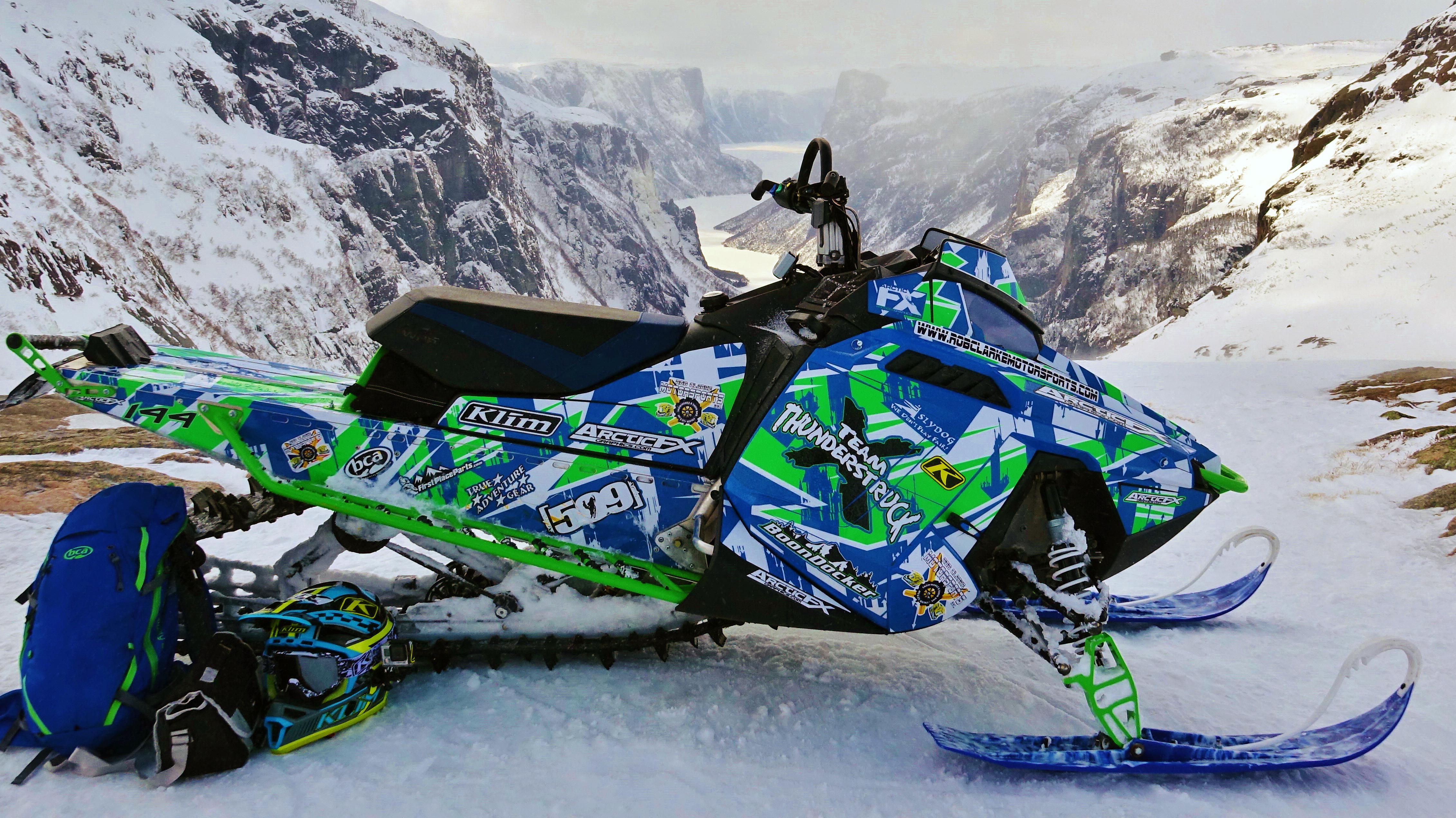 A Polaris Pro-Ride snowmobile with a white, lime, and blue Insidious custom vinyl wrap.