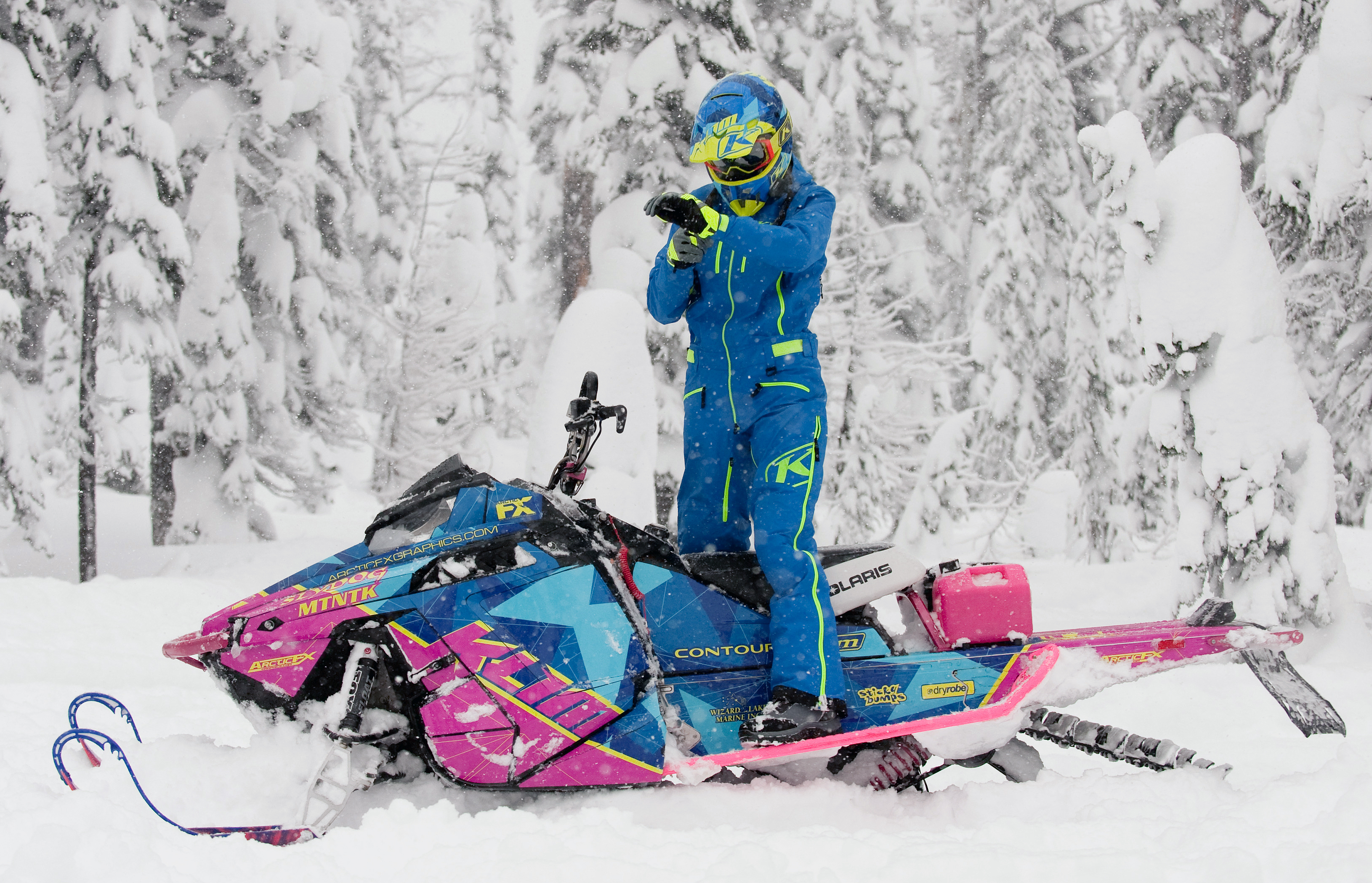 A Polaris Pro-Ride snowmobile with a blue, pink, and lime squeeze Klim F3 Camo custom vinyl wrap.