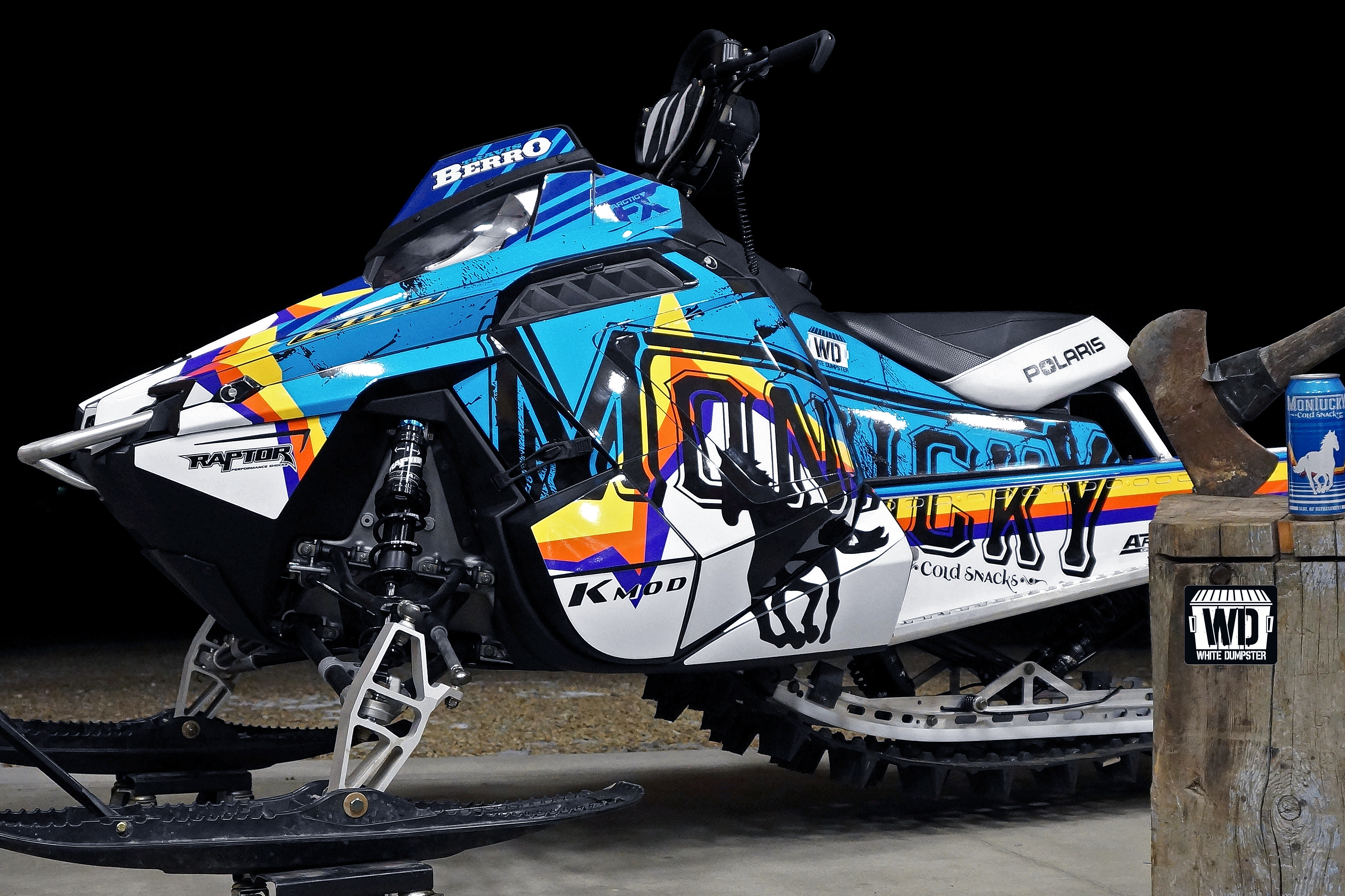 A Polaris Pro-Ride snowmobile with a blue, white, black, and yellow Montucky Cold Snacks beer custom vinyl wrap.