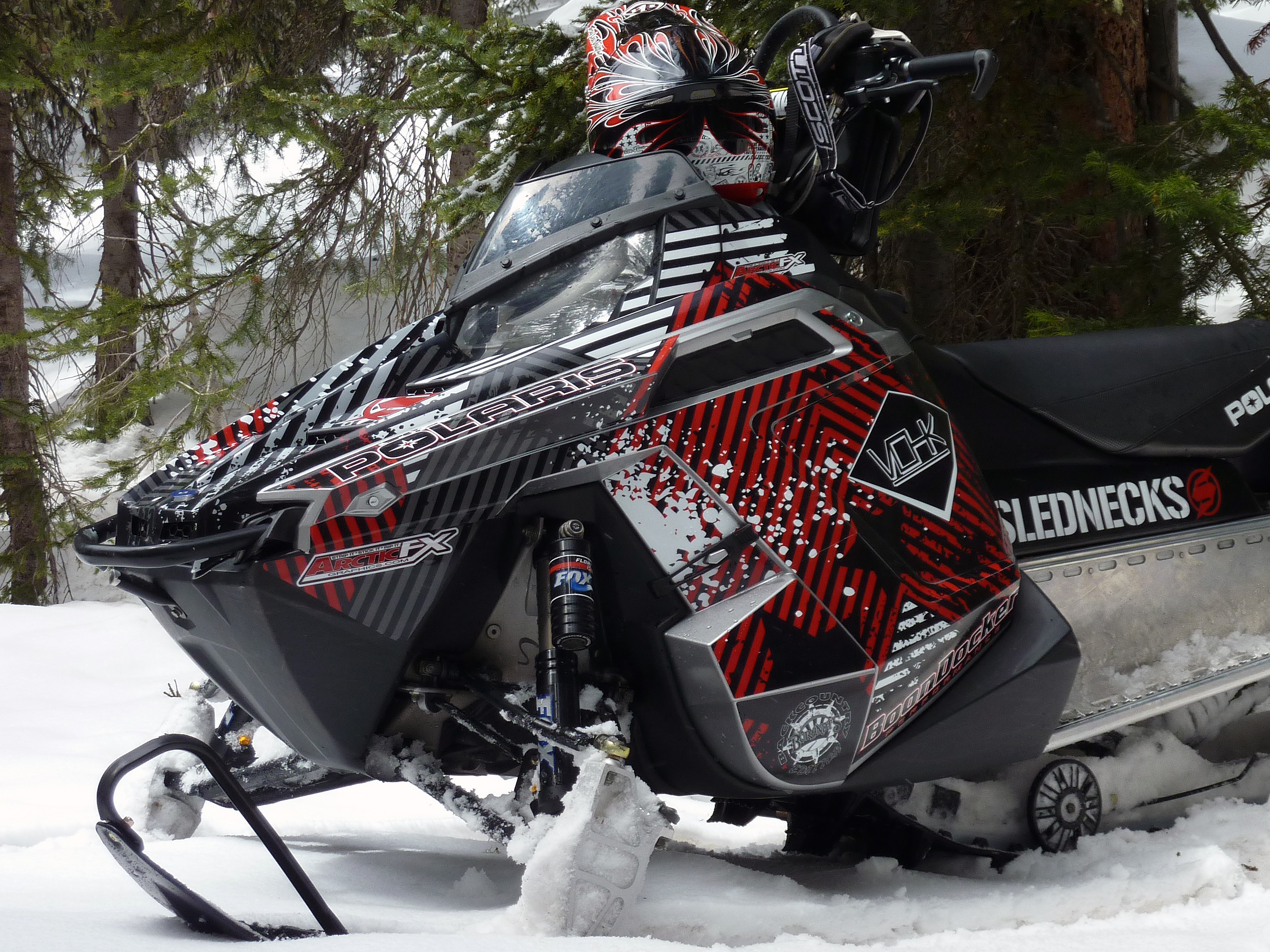 A Polaris Pro-Ride snowmobile with a red, white, and black Point Blank custom vinyl wrap.