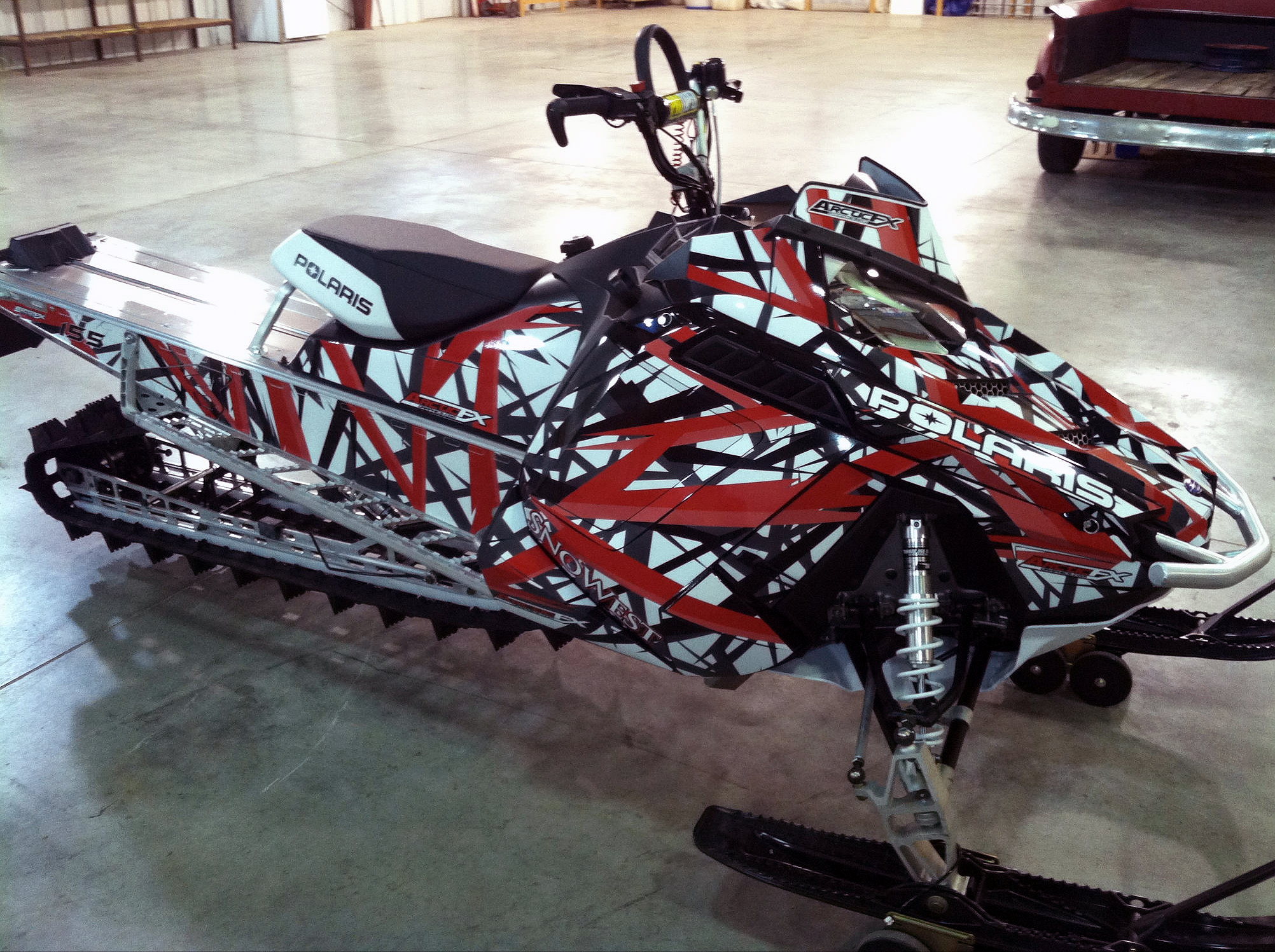 A Polaris Pro-Ride snowmobile with a red, white, and black Shattered Illusion custom vinyl wrap.