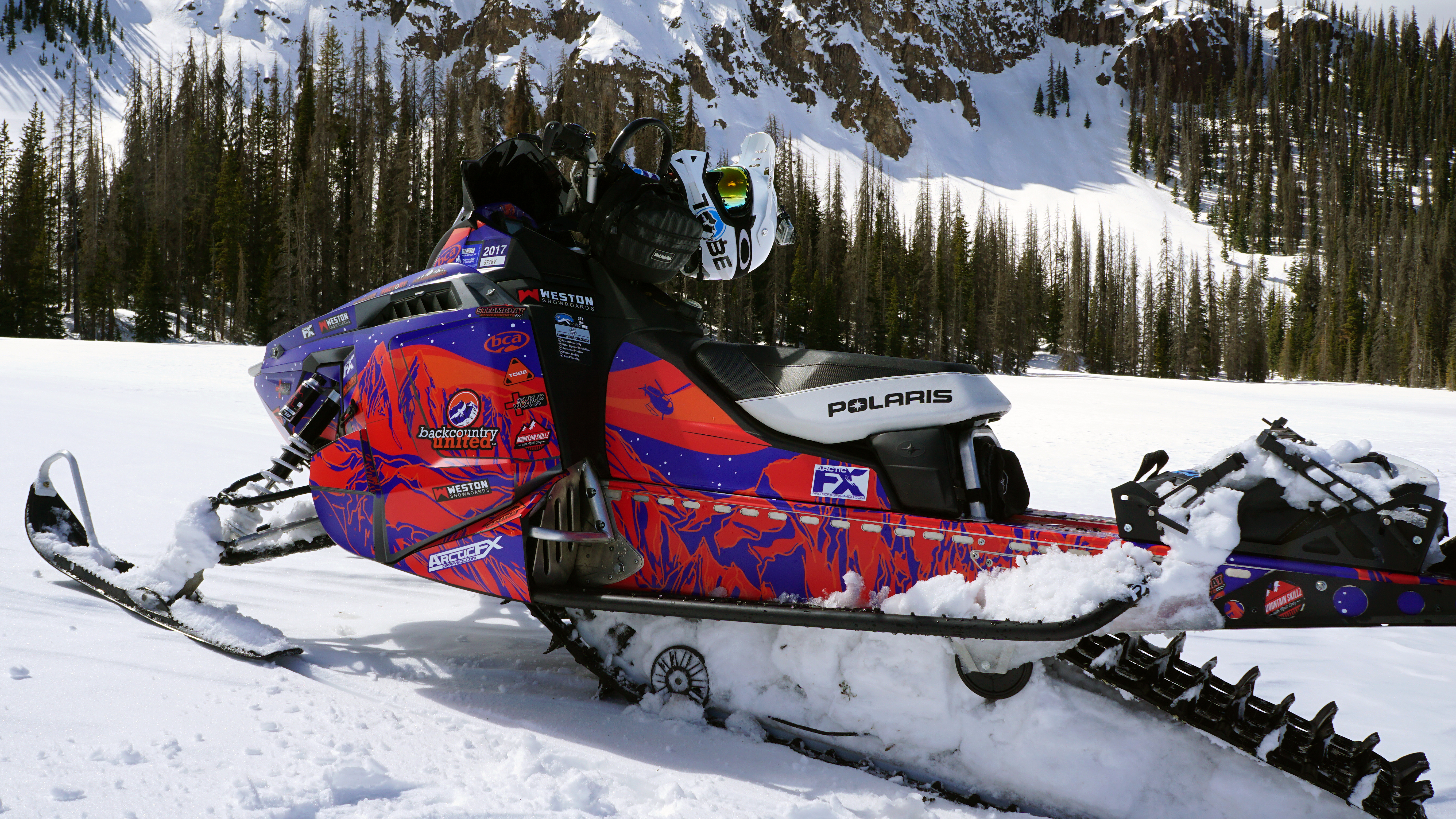 A Polaris Pro-Ride snowmobile with a purple and orange Sherman AK Assault custom vinyl wrap.