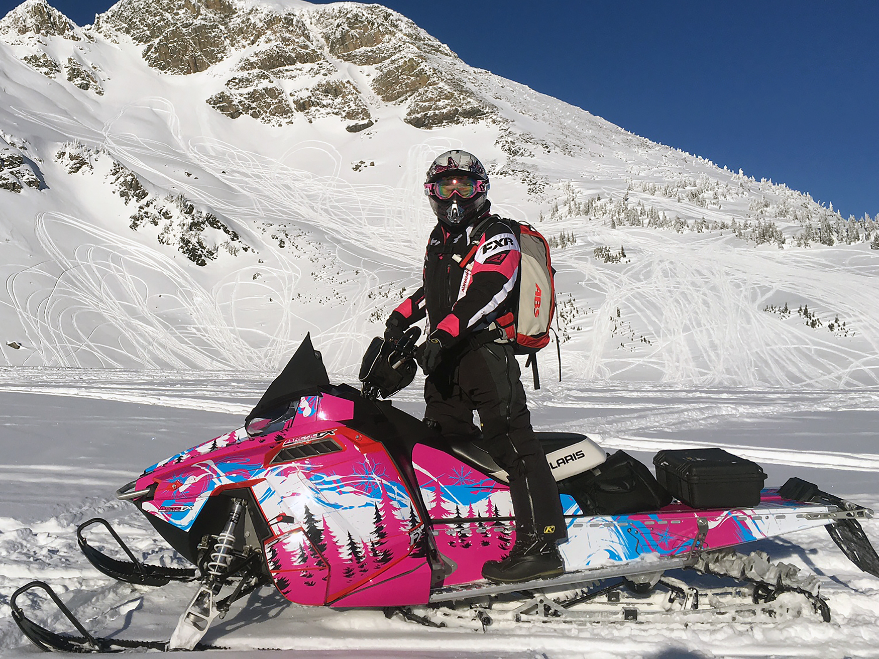 A Polaris Pro-Ride snowmobile with a pink, blue, and white Sub Zero custom vinyl wrap.