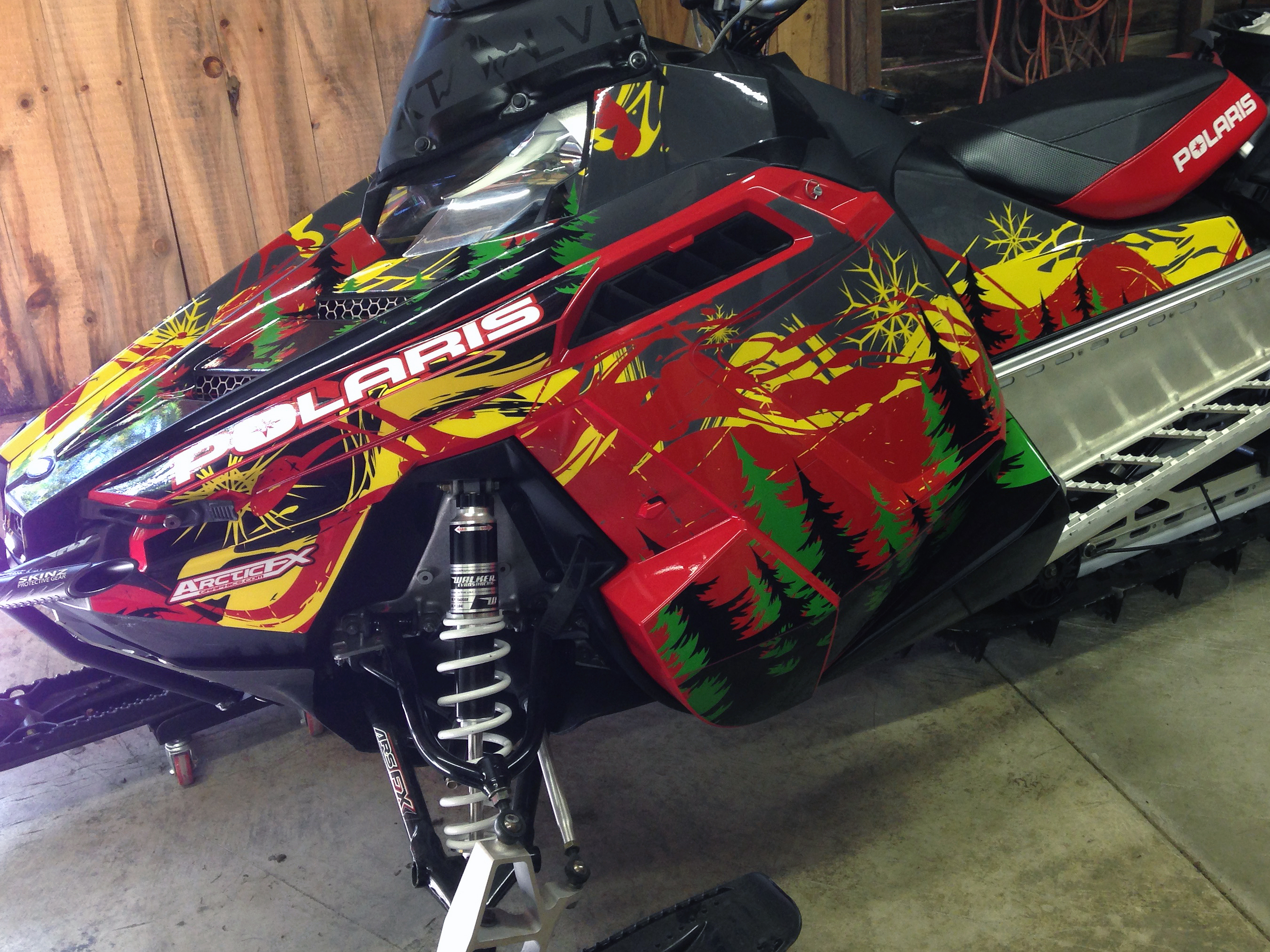A Polaris Pro-Ride snowmobile with a red, green, yellow, and black Sub Zero custom vinyl wrap.