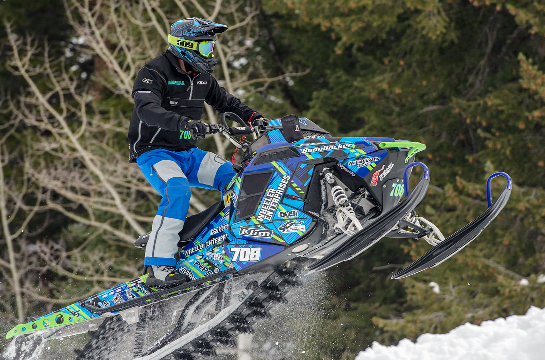 A Polaris Pro-Ride snowmobile with a lime, blue, and black Swerve City custom vinyl wrap.