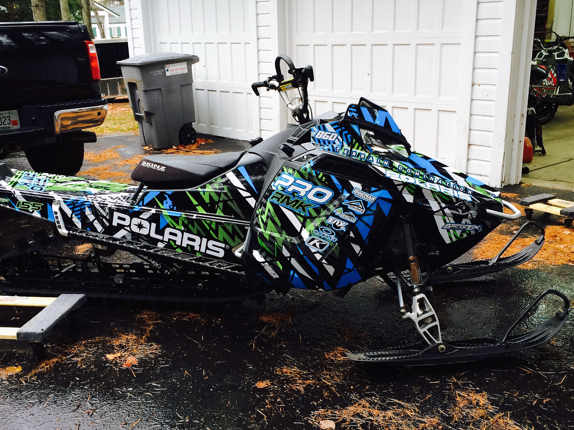 A Polaris Pro-Ride snowmobile with a lime, blue, and black Voltage custom vinyl wrap.