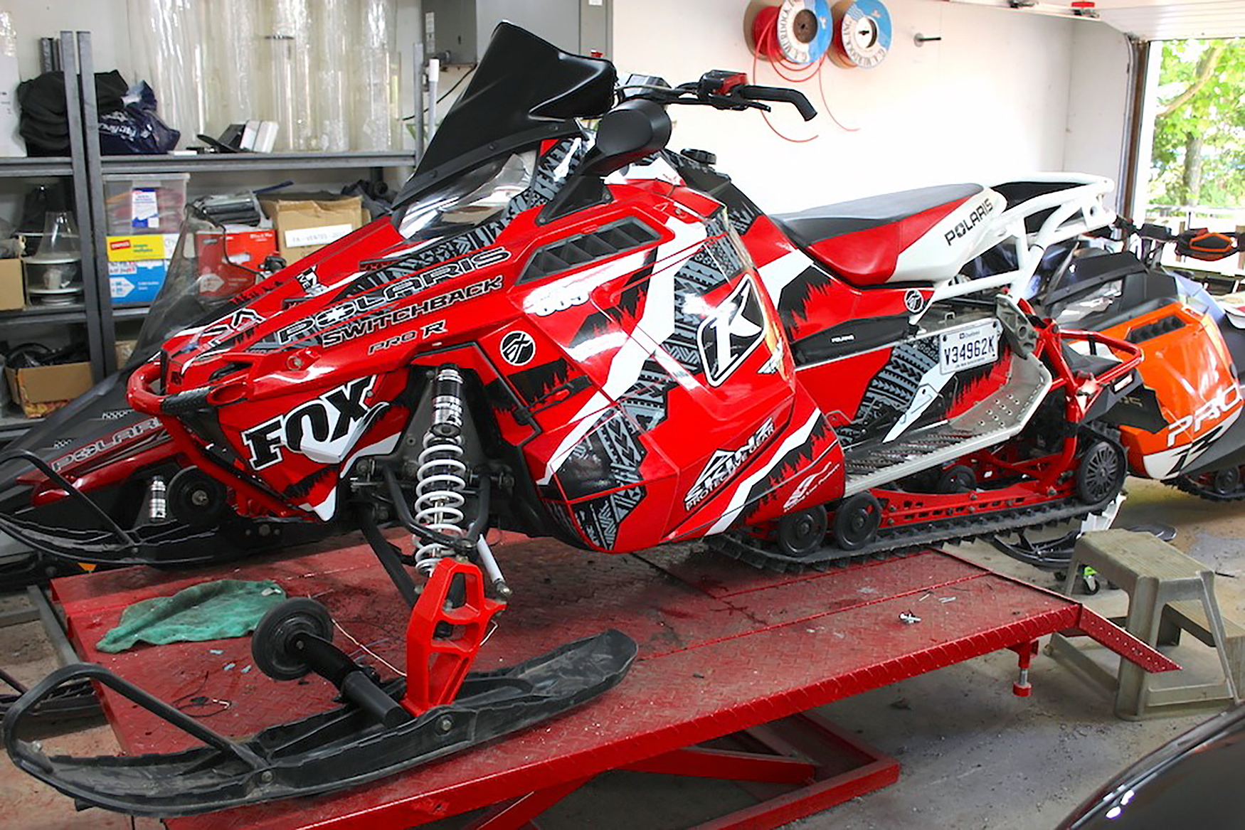 A Polaris Pro-Ride snowmobile with a black, red, and white Adams Alpine custom vinyl wrap.