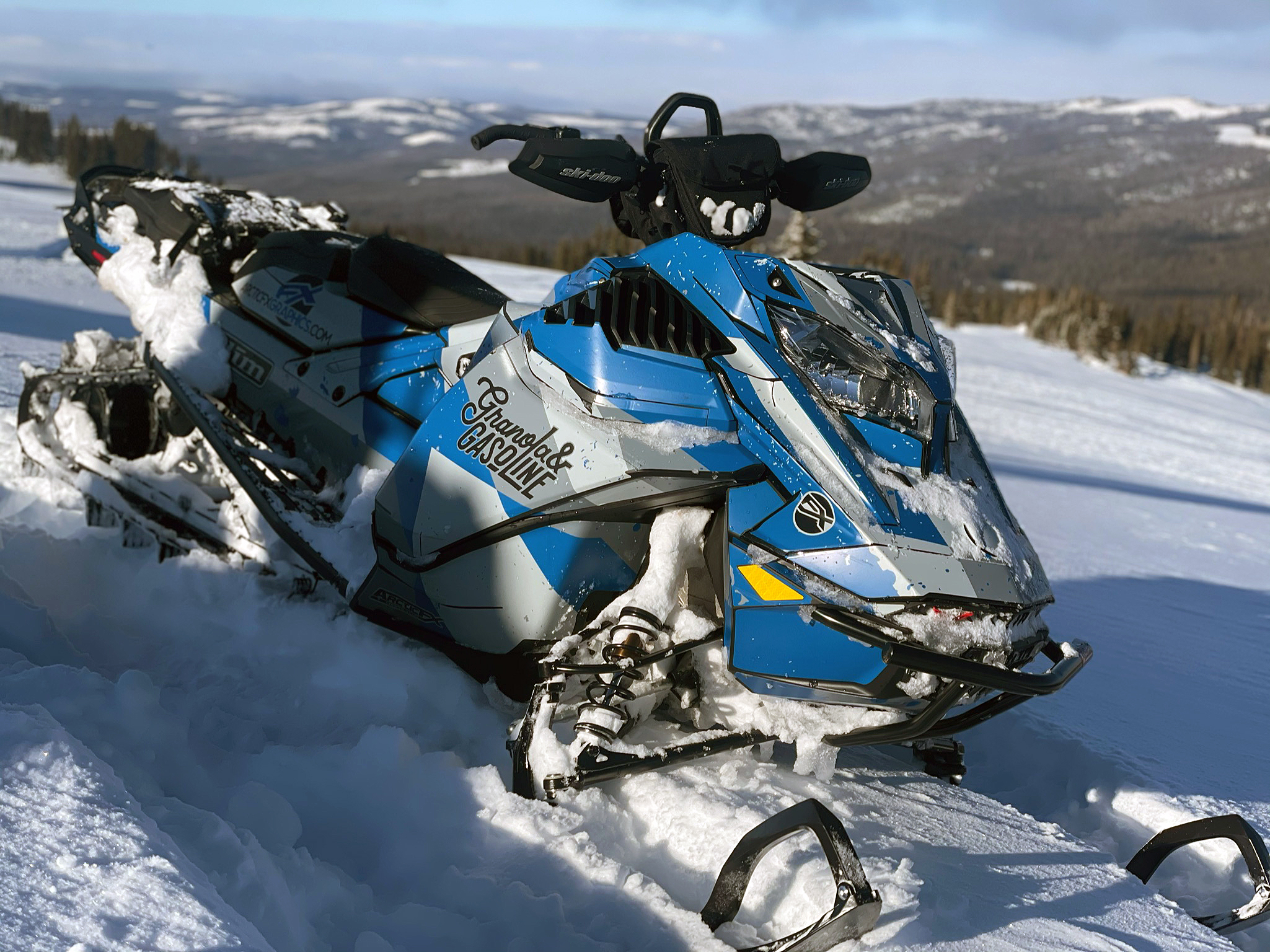 A Ski-Doo Gen4 Lightweight snowmobile with a blue, gray, and black Diversion custom vinyl wrap.