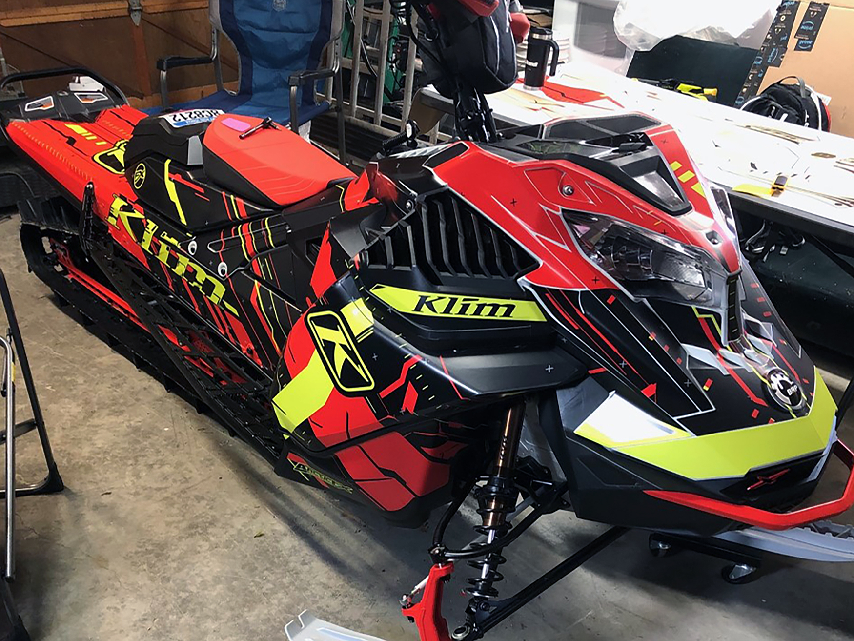A Ski-Doo Gen4 Lightweight snowmobile with a yellow, red, and black Klim Recoil custom vinyl wrap.