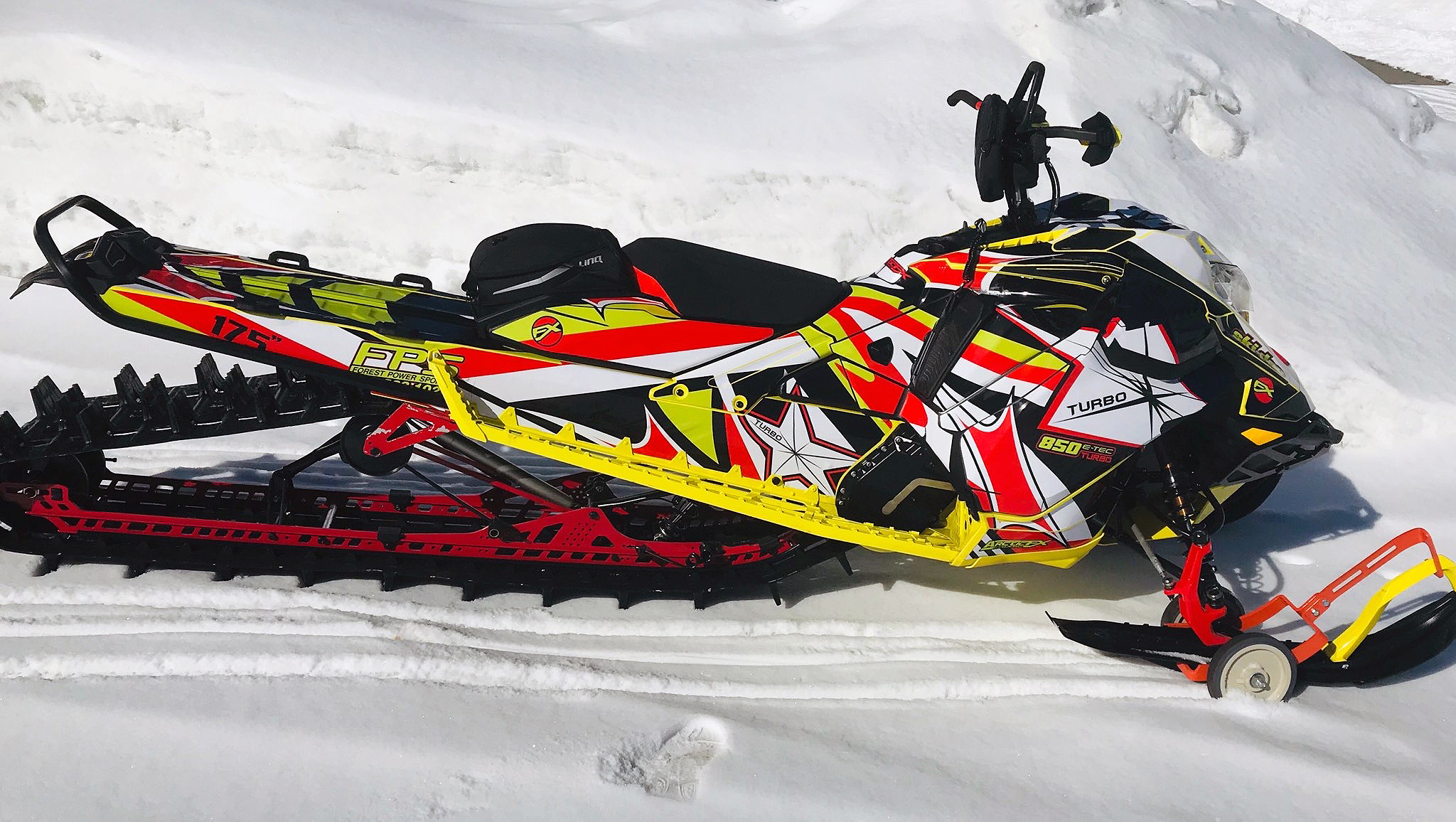 A Ski-Doo Gen4 Lightweight snowmobile with a yellow, red, and white Star custom vinyl wrap.