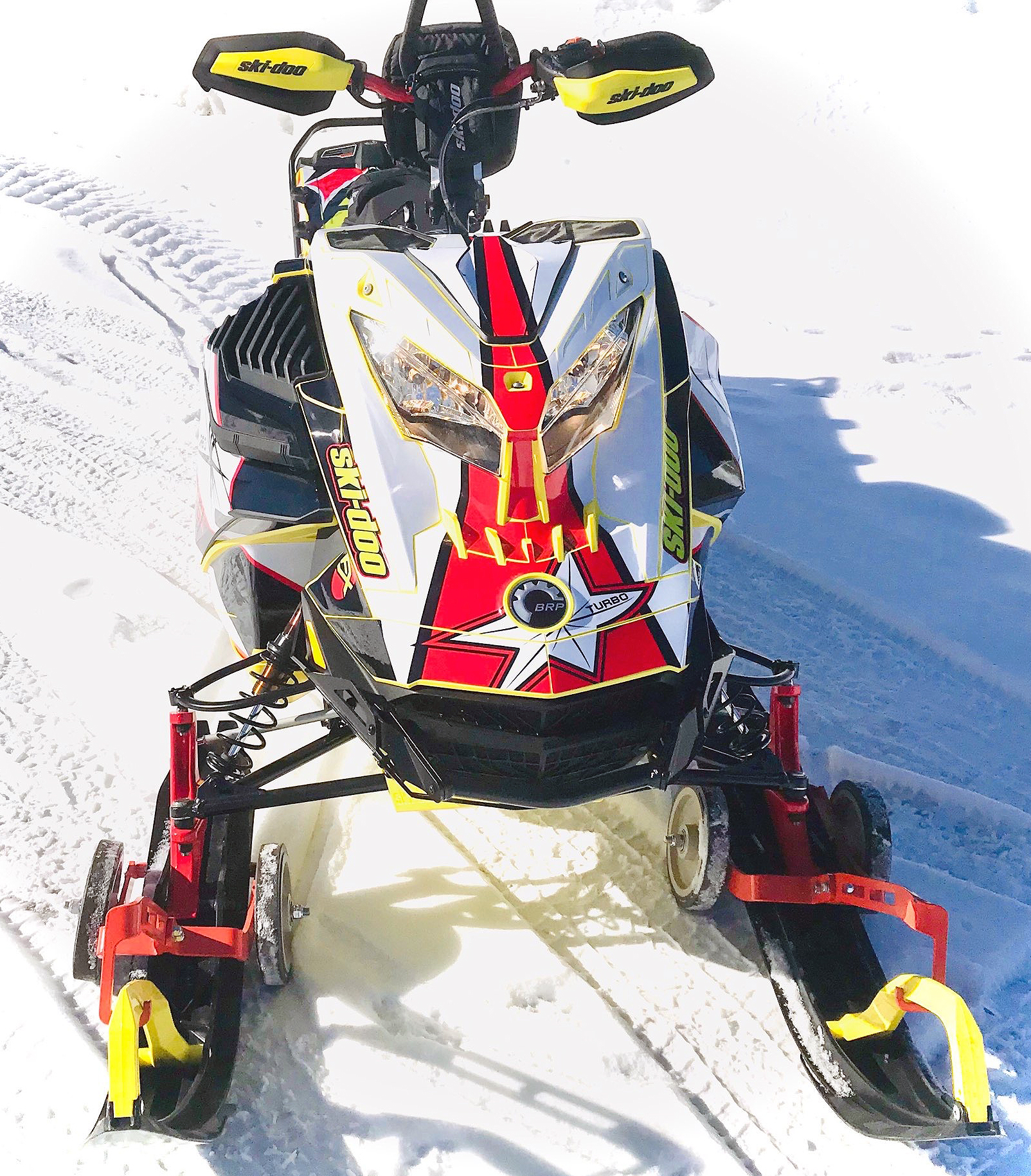 A Ski-Doo Gen4 Lightweight snowmobile with a yellow, red, and white Star custom vinyl wrap.