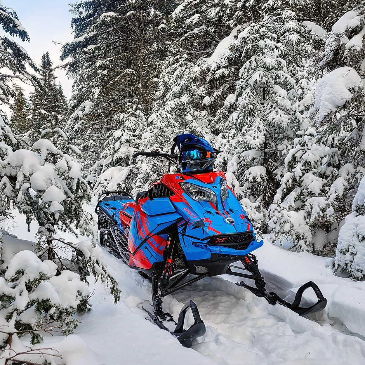 A Ski-Doo Gen4 Lightweight snowmobile with a blue, red, and black Teton custom vinyl wrap.