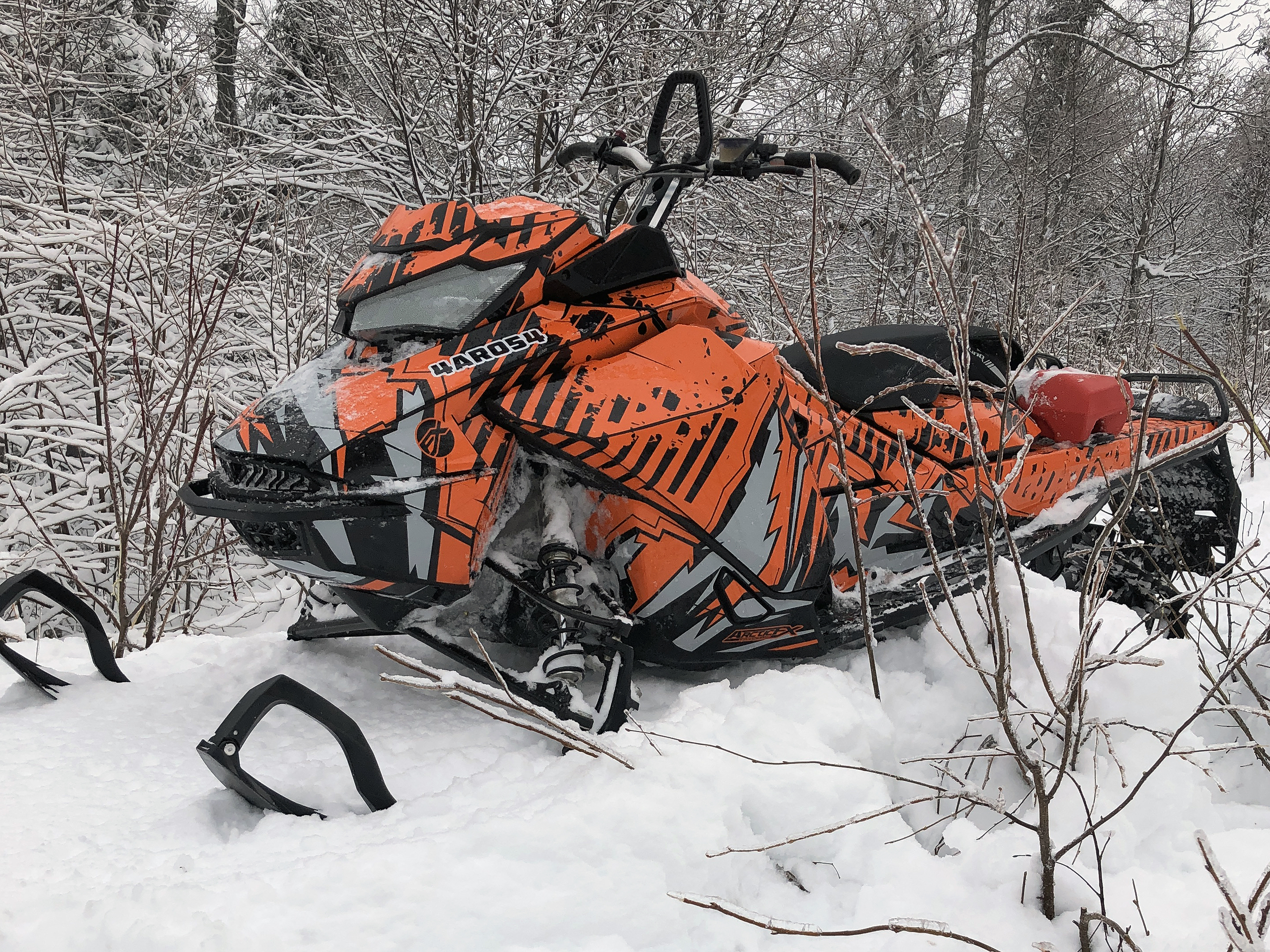A Ski-Doo Gen4 Narrow Body snowmobile with a orange, black, and gray Altitude custom vinyl wrap.