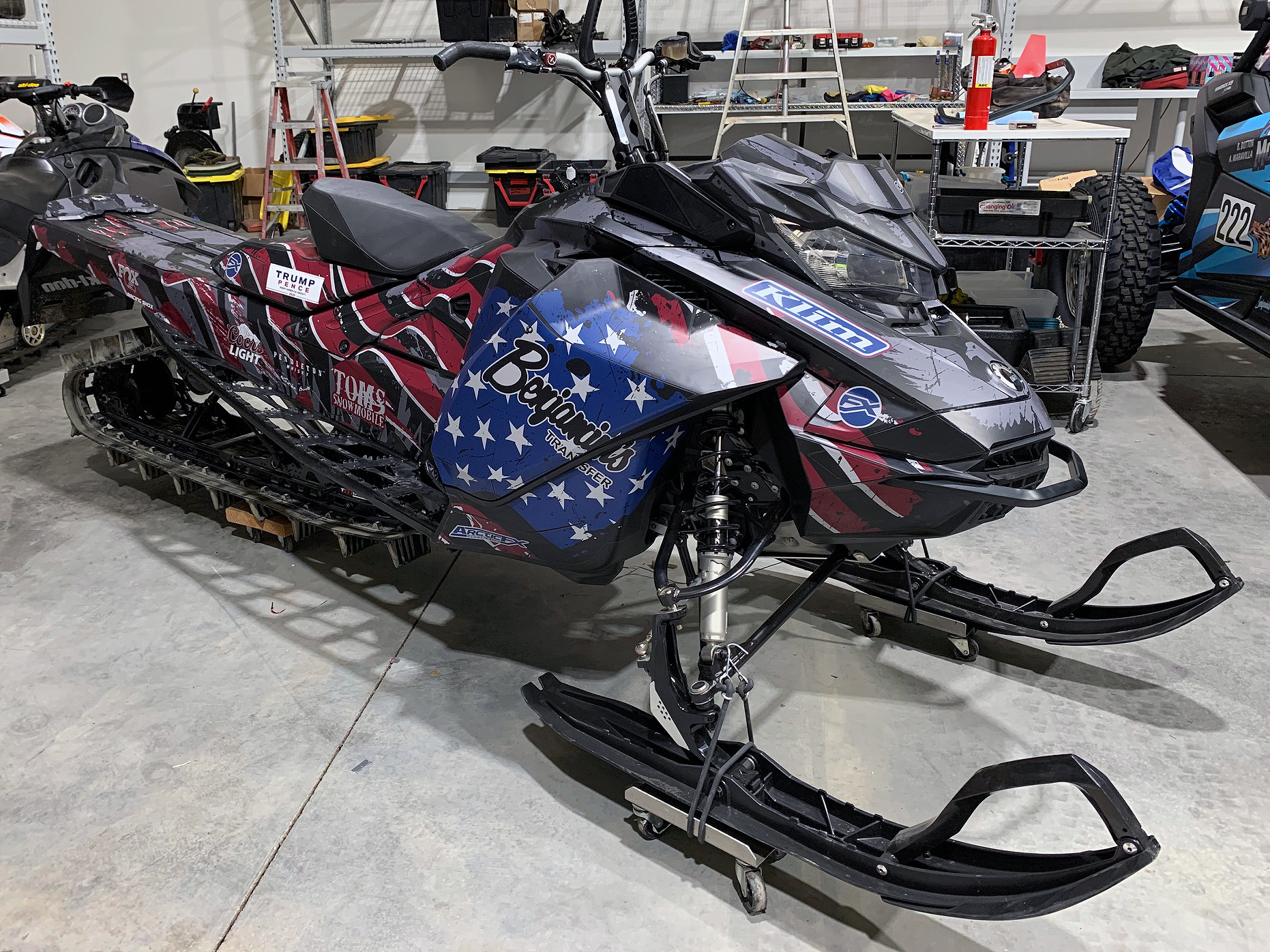 A Ski-Doo Gen4 Narrow Body snowmobile with a red, white, blue, and black American Flag custom vinyl wrap.