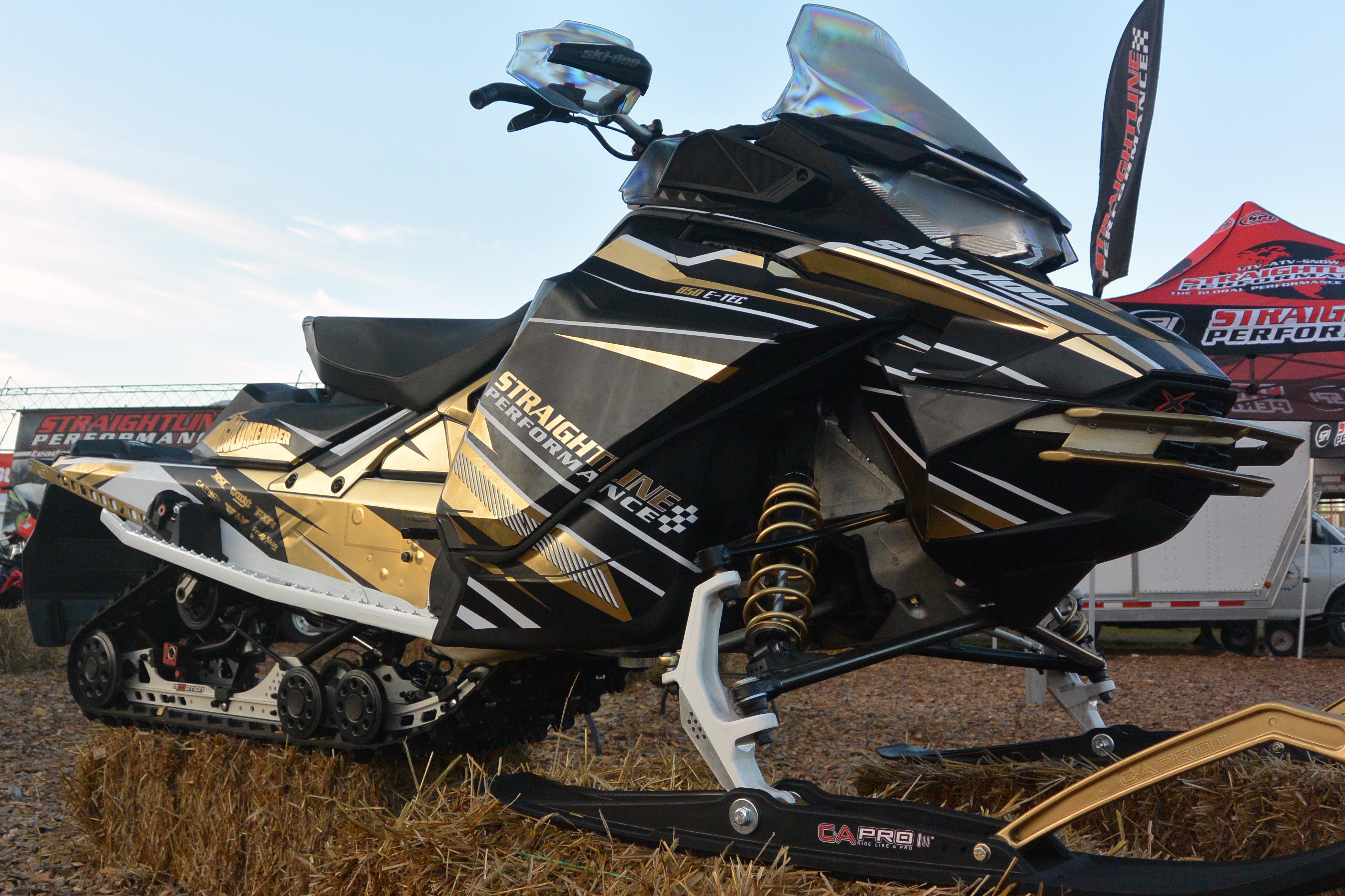 A Ski-Doo Gen4 Narrow Body snowmobile with a gold, white, and black Bred2Win custom vinyl wrap.