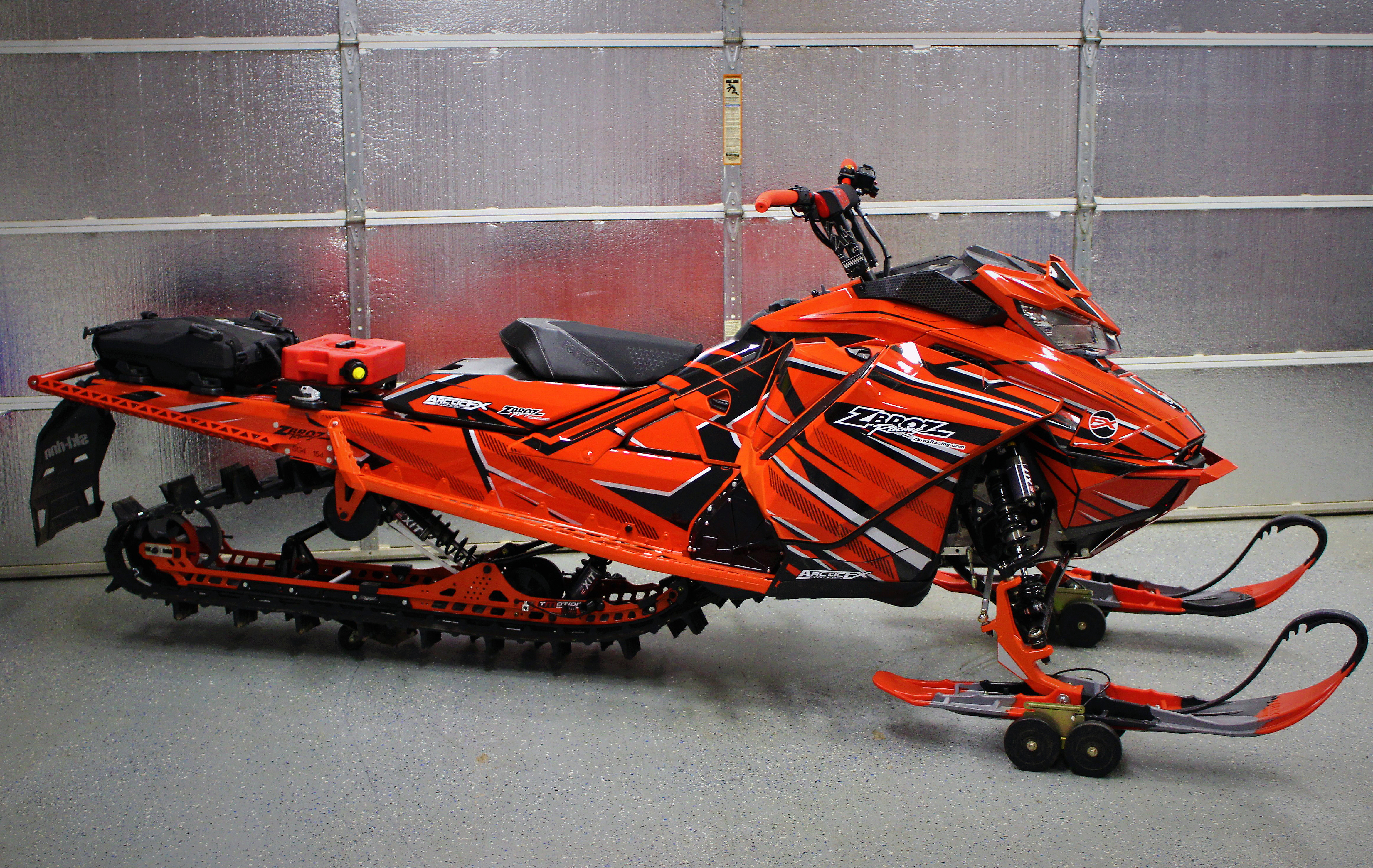 A Ski-Doo Gen4 Narrow Body snowmobile with a red, black, and gray Bred2Win custom vinyl wrap.