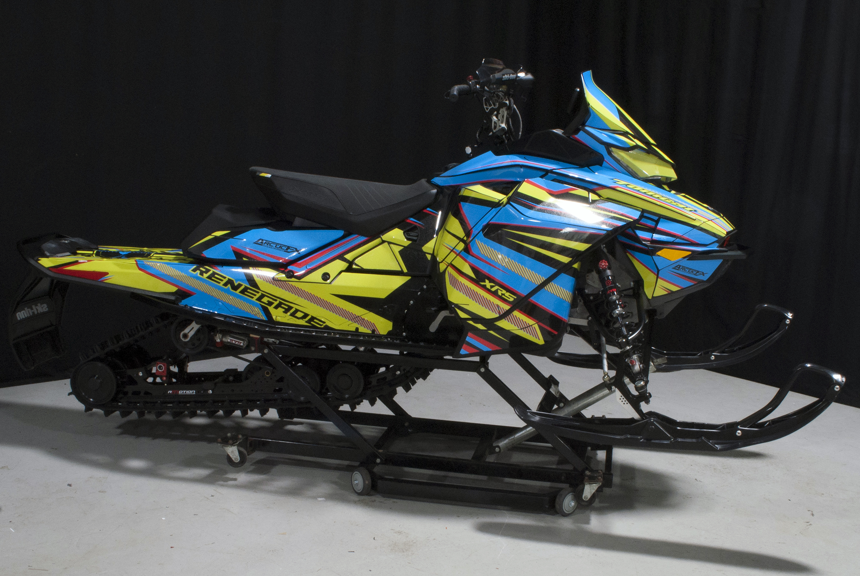 A Ski-Doo Gen4 Narrow Body snowmobile with a yellow, blue, and red Bred2Win custom vinyl wrap.