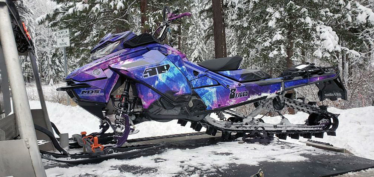 A Ski-Doo Gen4 Narrow Body snowmobile with a blue and purple Cosmic Camo custom vinyl wrap.