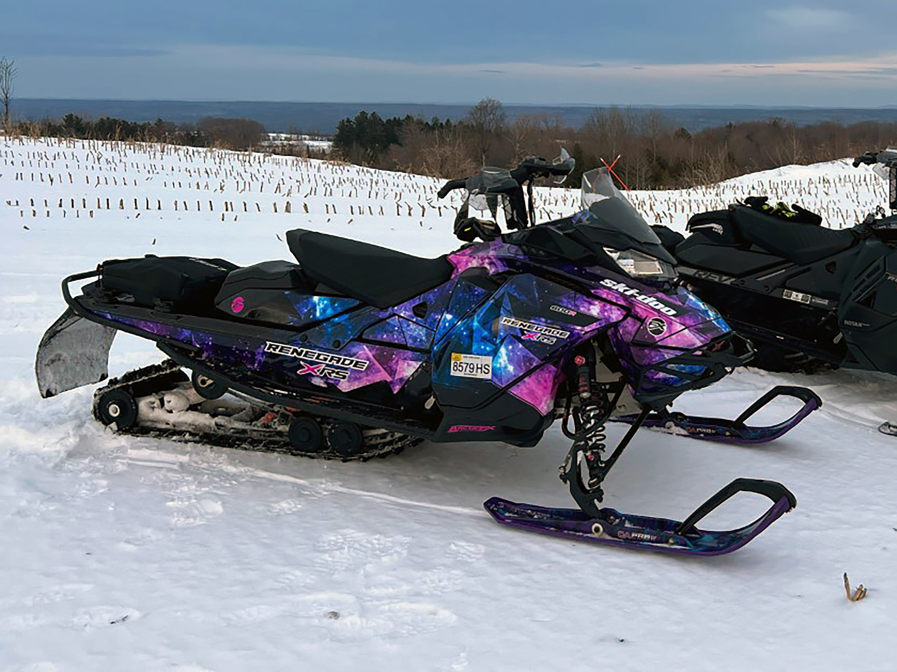 A Ski-Doo Gen4 Narrow Body snowmobile with a blue, purple, and pink Cosmic Camo galaxy custom vinyl wrap.