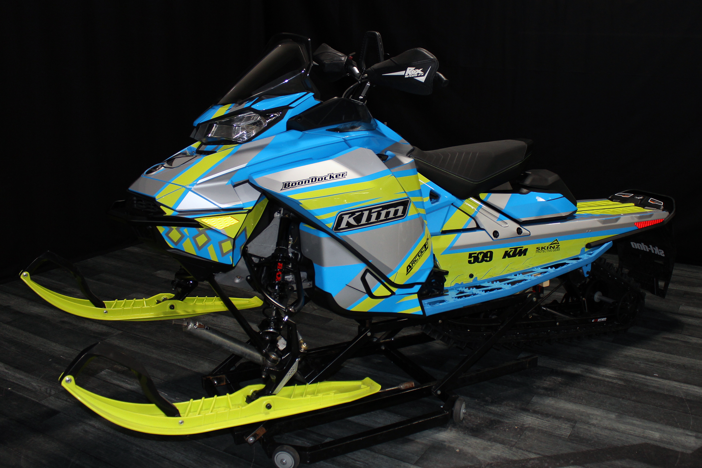 A Ski-Doo Gen4 Narrow Body snowmobile with a octane blue, manta, and gray Curtis Mountain King custom vinyl wrap.