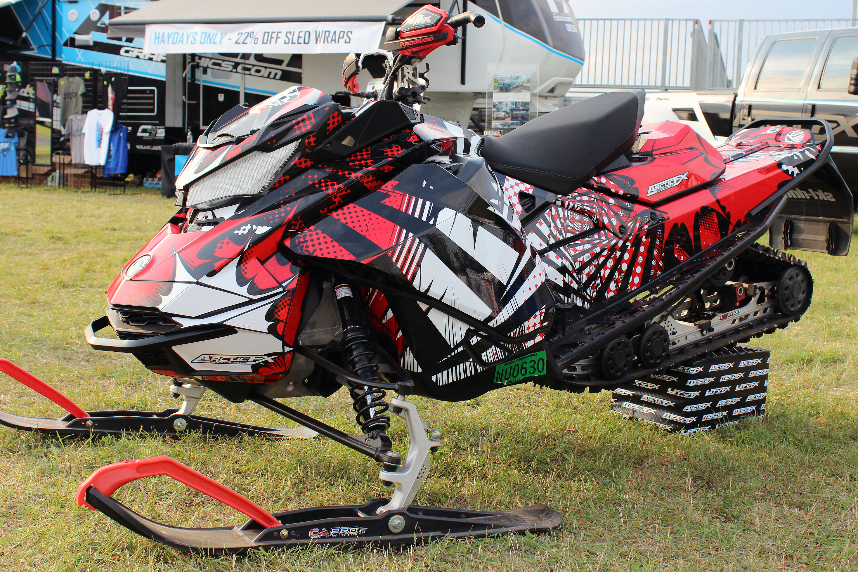 A Ski-Doo Gen4 Narrow Body snowmobile with a red, white, and black Delirious custom vinyl wrap.