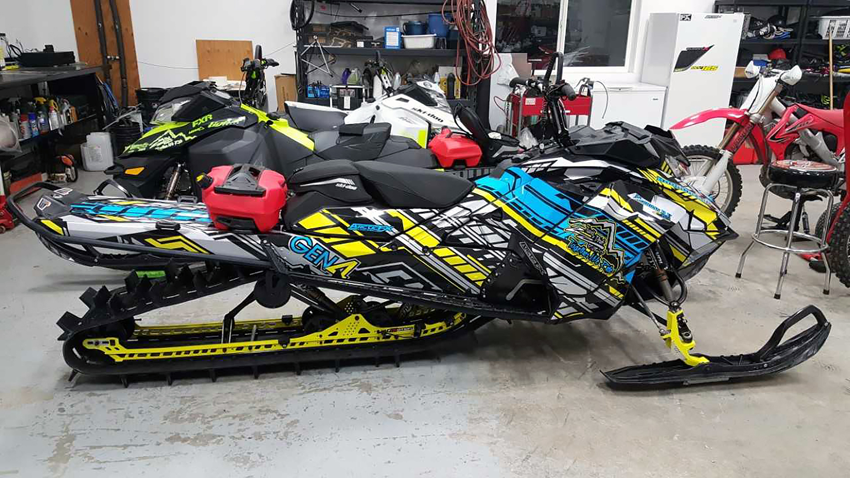 A Ski-Doo Gen4 Narrow Body snowmobile with a gray, yellow, blue, and black Evasion custom vinyl wrap.