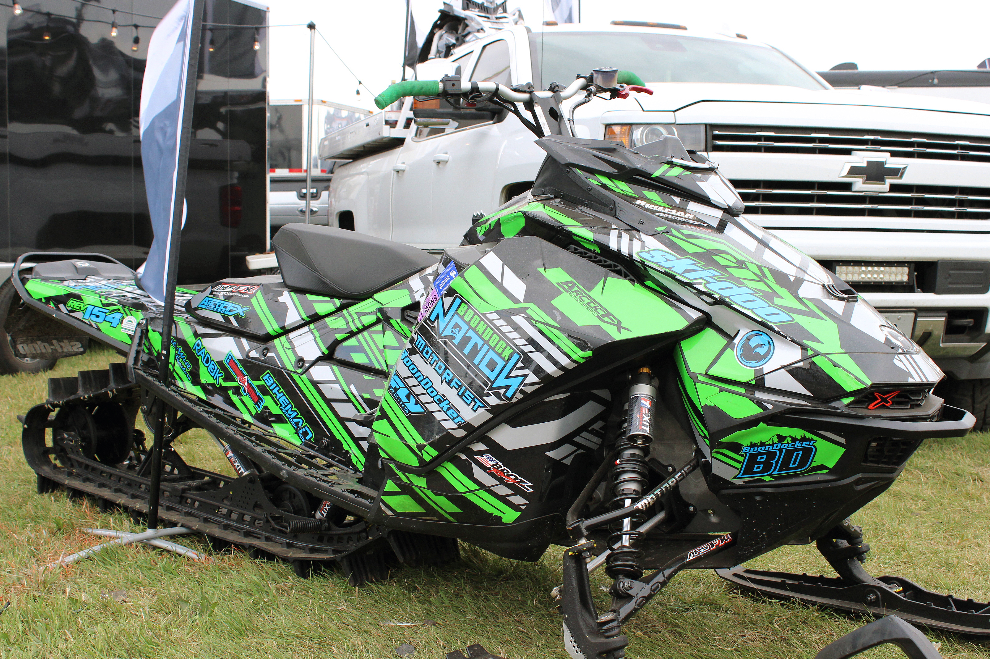 A Ski-Doo Gen4 Narrow Body snowmobile with a green, gray, and black Evasion custom vinyl wrap.