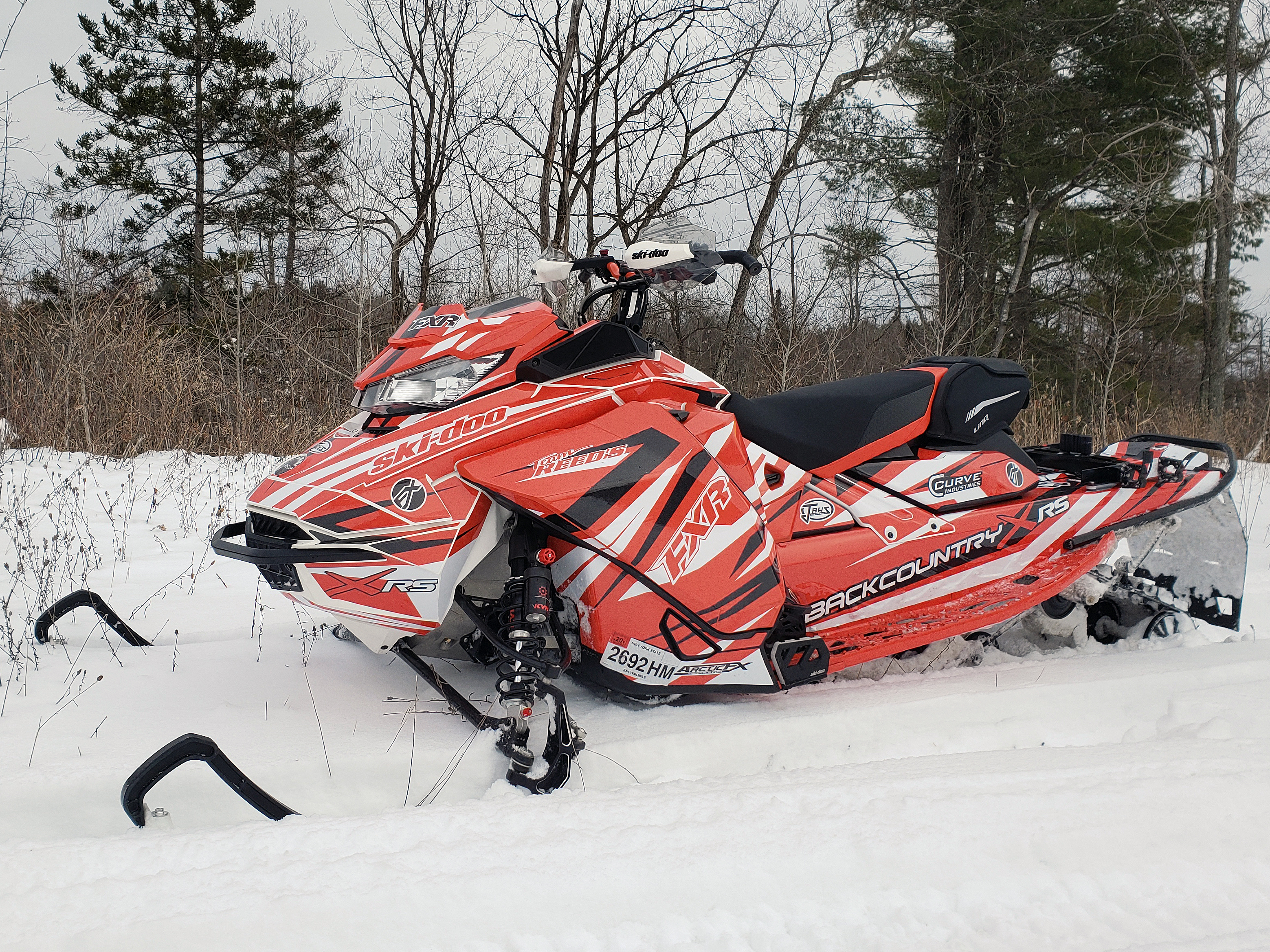 A Ski-Doo Gen4 Narrow Body snowmobile with a red, black, and white Burandt Evolution custom vinyl wrap.