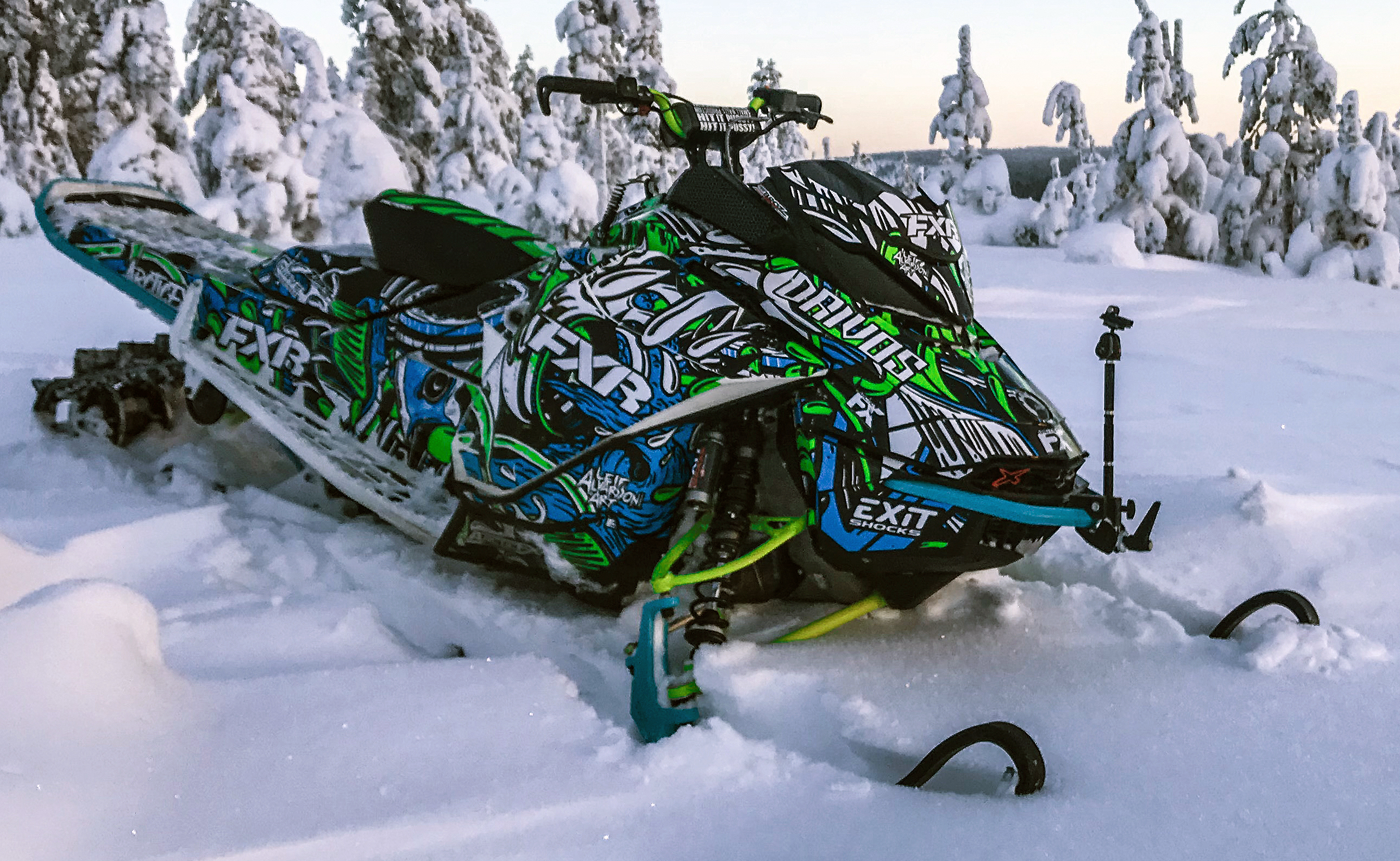 A Ski-Doo Gen4 Narrow Body snowmobile with a blue, green, white, and black Onasch Fueled custom vinyl wrap.