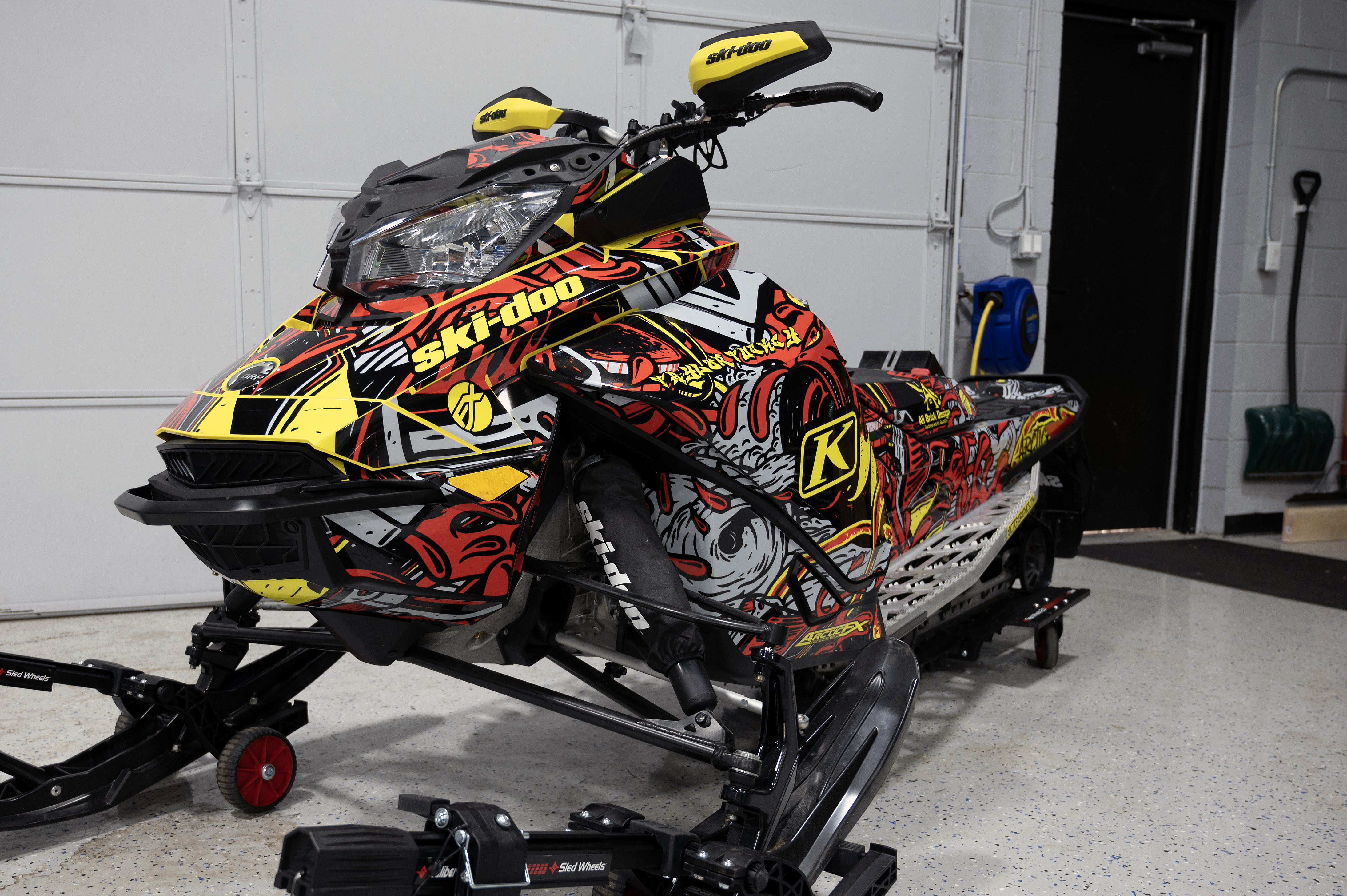 A Ski-Doo Gen4 Narrow Body snowmobile with a gray, red, and yellow Onasch Fueled custom vinyl wrap.
