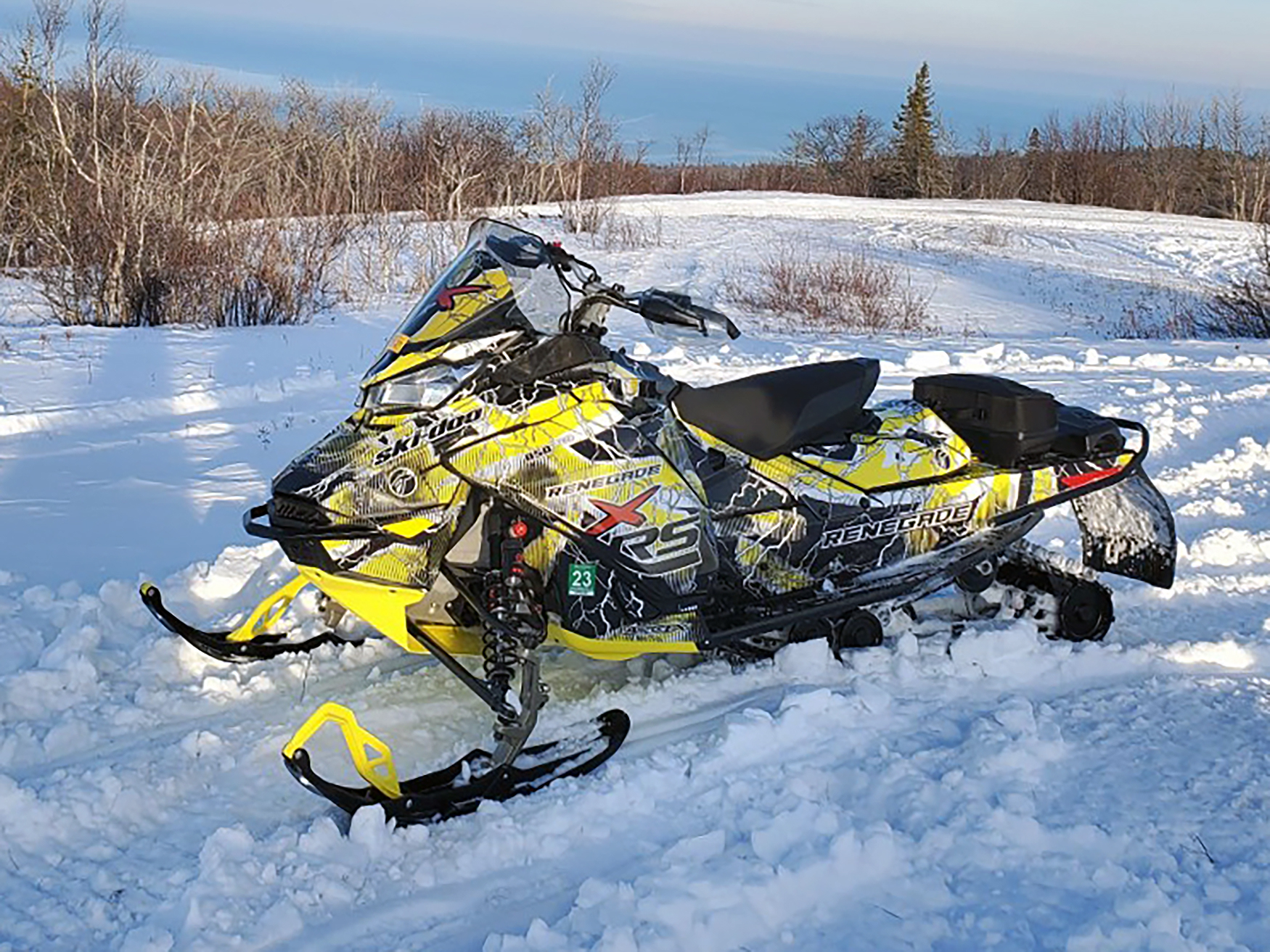 A Ski-Doo Gen4 Narrow Body snowmobile with a black, white, and yellow Hard Rain custom vinyl wrap.