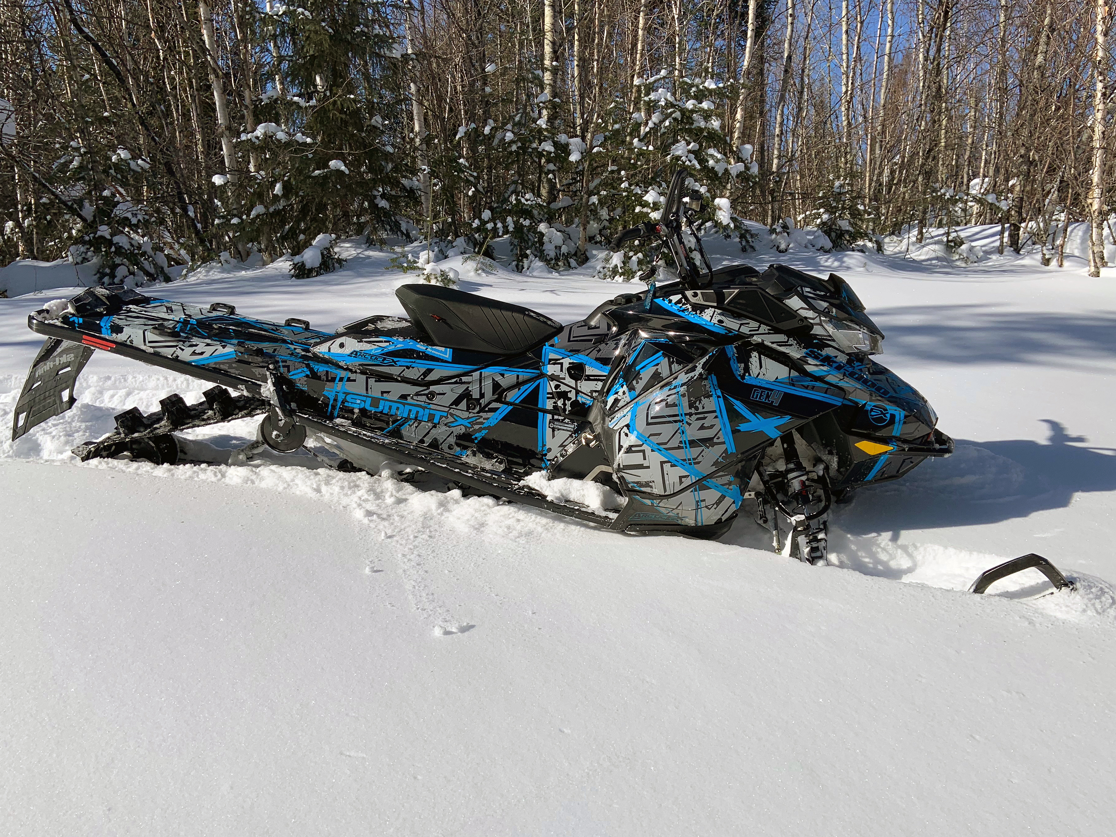 A Ski-Doo Gen4 Narrow Body snowmobile with a black, gray, and blue Havoc custom vinyl wrap.