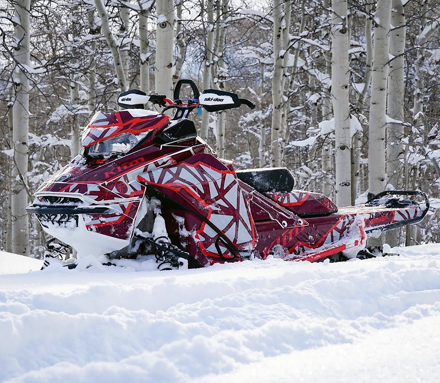 A Ski-Doo Gen4 Narrow Body snowmobile with a red and gray Klim Demolish custom vinyl wrap.