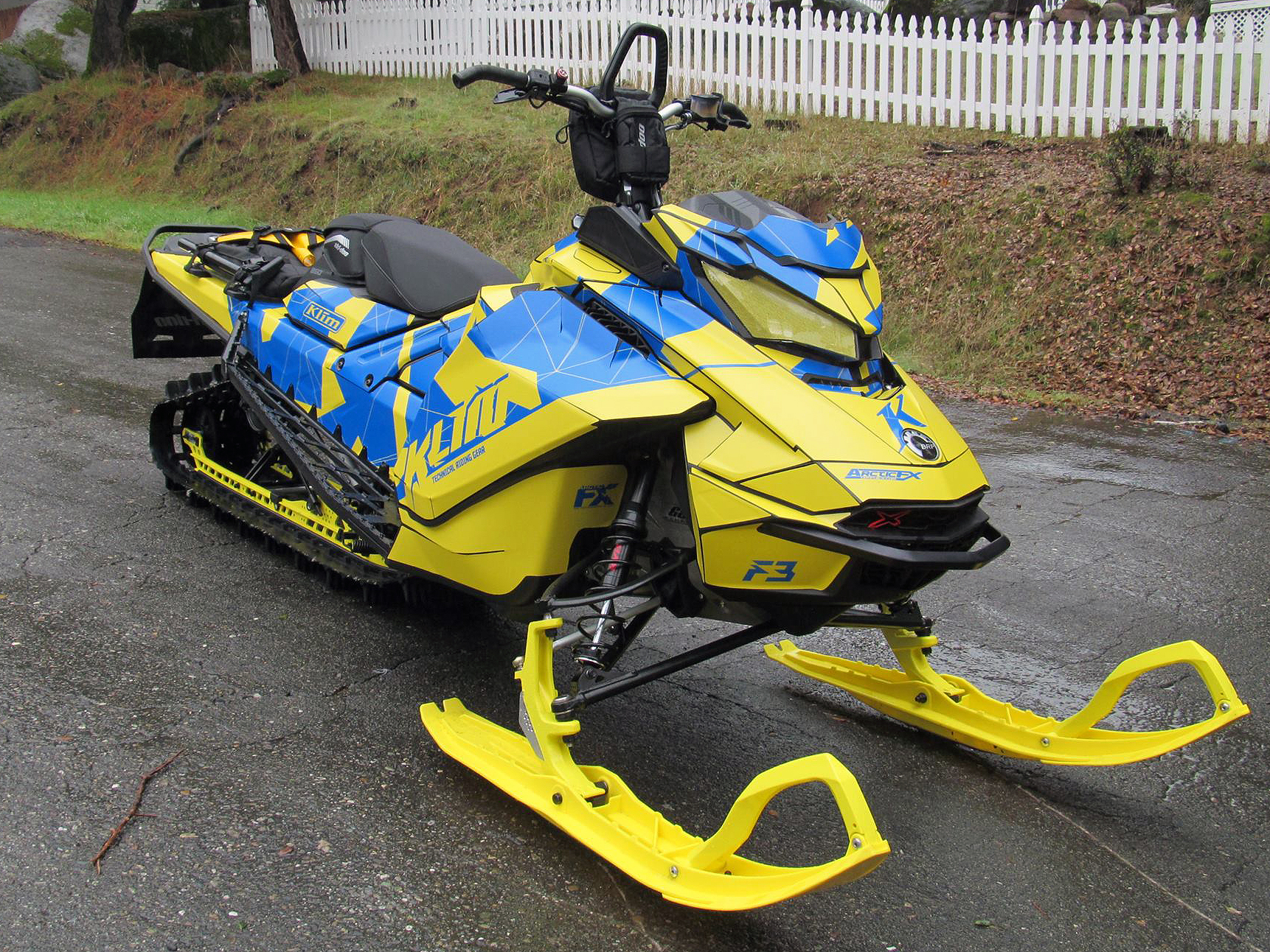 A Ski-Doo Gen4 Narrow Body snowmobile with a yellow and octane blue Klim F3 Camo custom vinyl wrap.