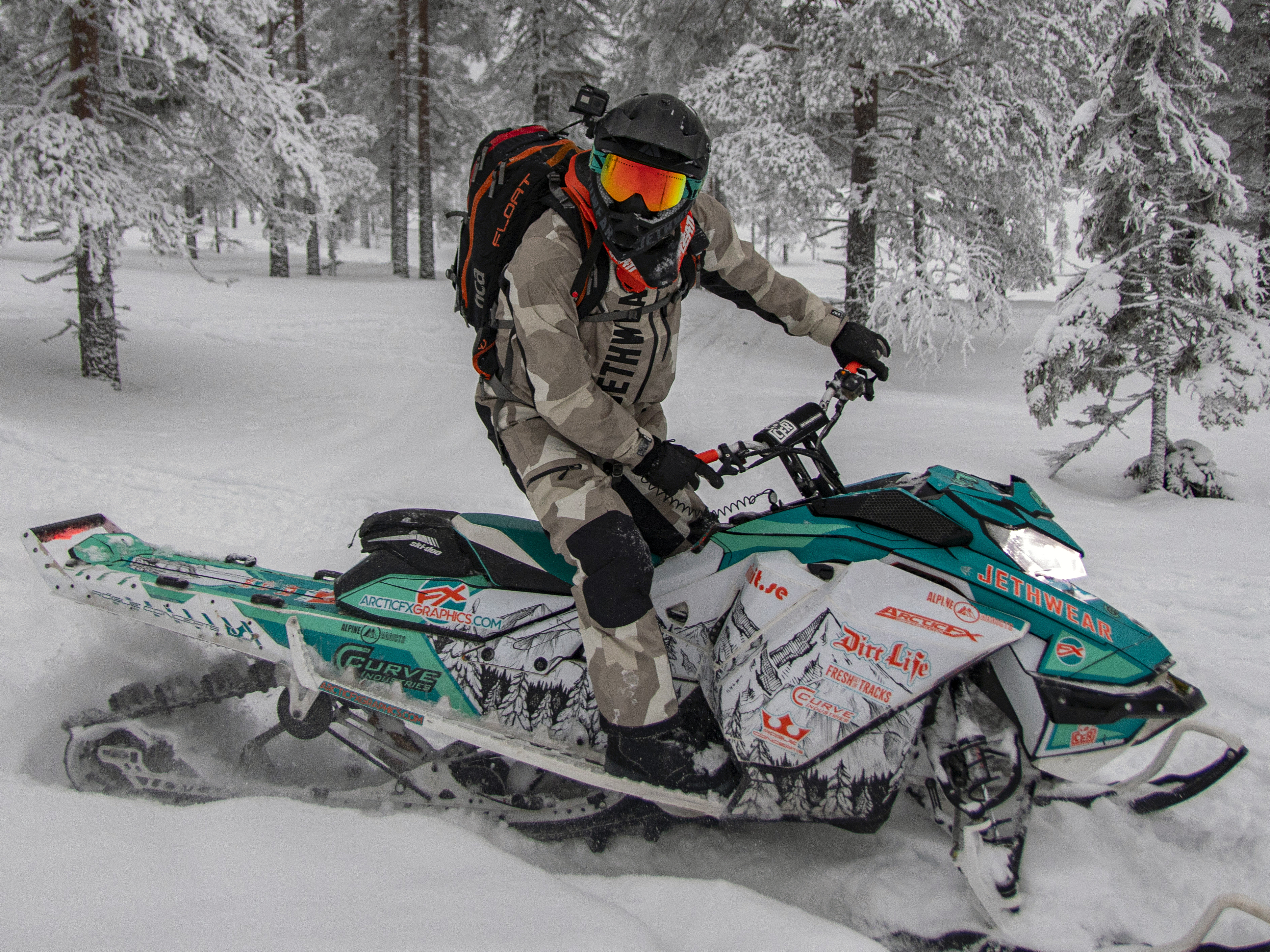 A Ski-Doo Gen4 Narrow Body snowmobile with a aqua, orange, white, and black Andy Thomas Peaked custom vinyl wrap.